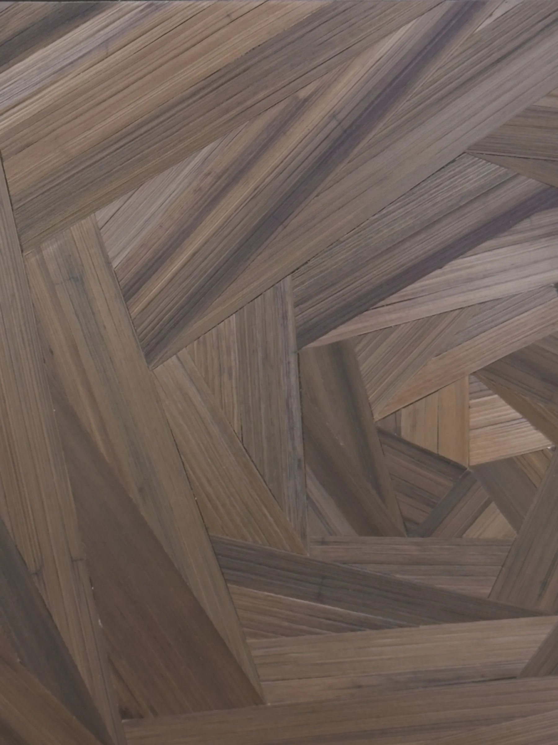Close-up of hand-laid rye straw marquetry surface showing deep brown tonal variations, grain texture, and geometric facets of the asymmetrical spiral
