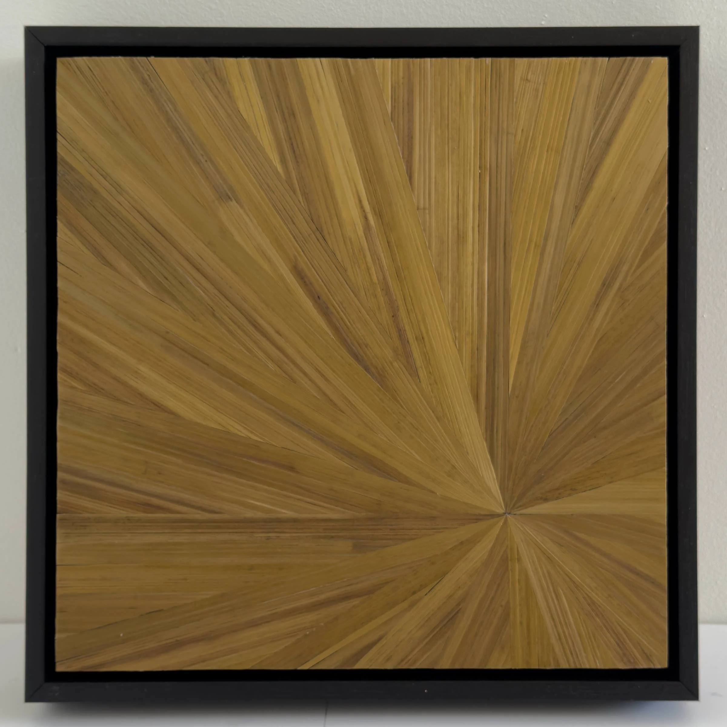 Contemporary abstract straw marquetry artwork in gold. Beautifully luminous radial pattern. 12in x 12in. Framed in black.