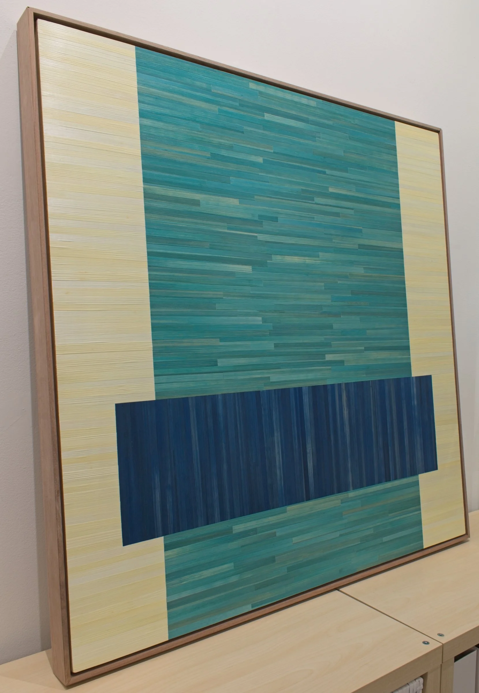 Side view of Color Block straw marquetry artwork in blue and teal. Float framed in walnut.