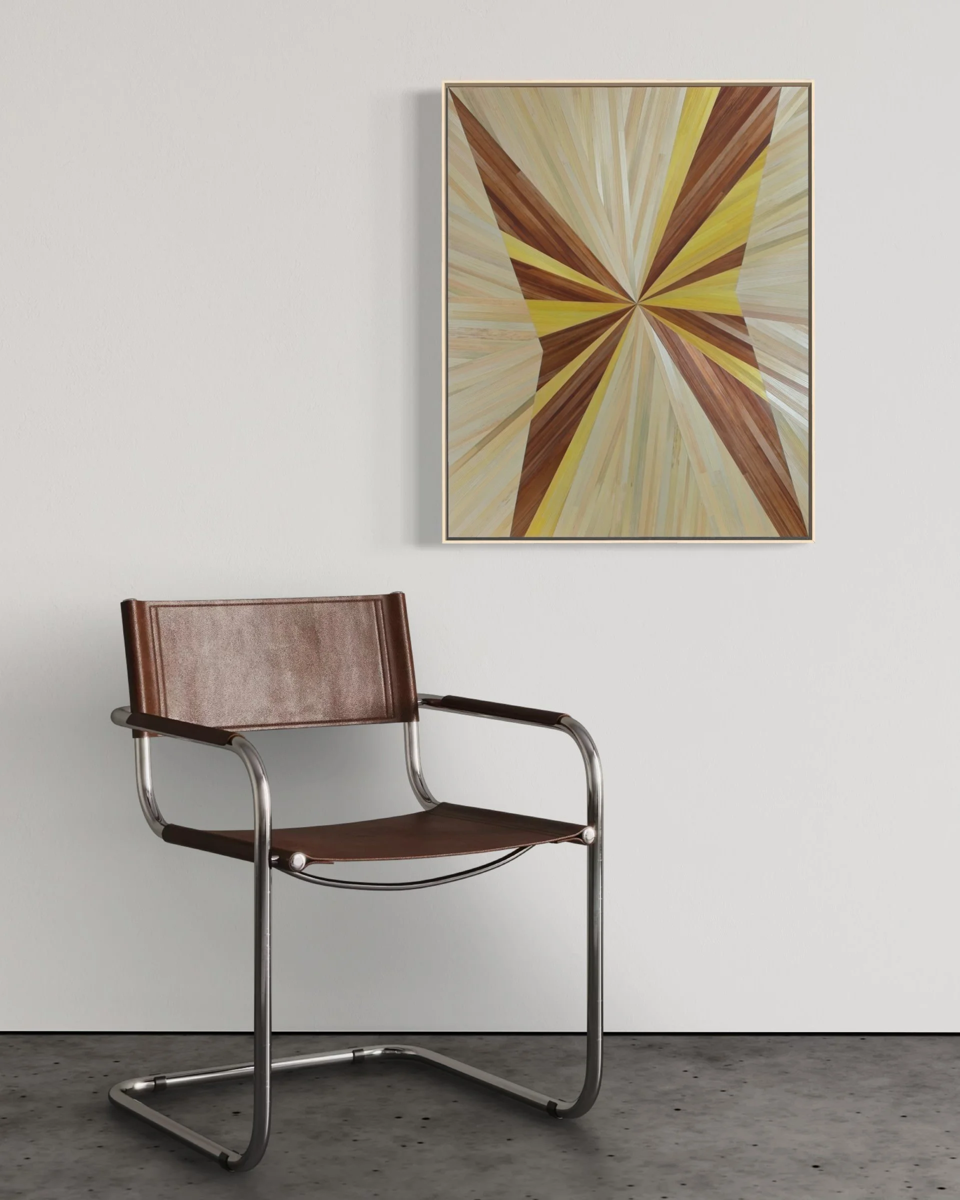 Straw marquetry artwork installed on a plain white wall above a modern chair — abstract radial burst wall art in yellow and brown tones, float framed in maple, by New England artist Sarah Schwartz