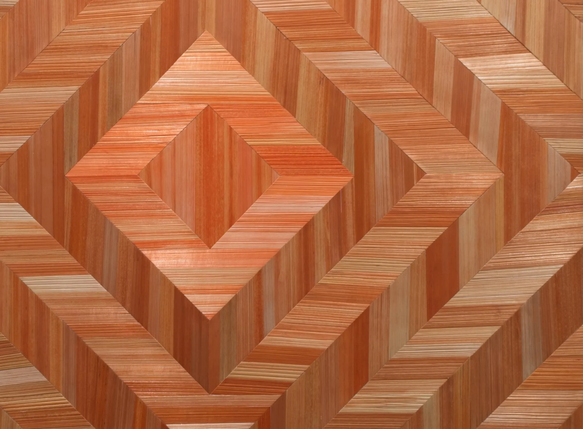 Detail view of hand-dyed rye straw marquetry artwork in a chevon pattern, with a palette of copper and rust tones, and showing the natural straw texture