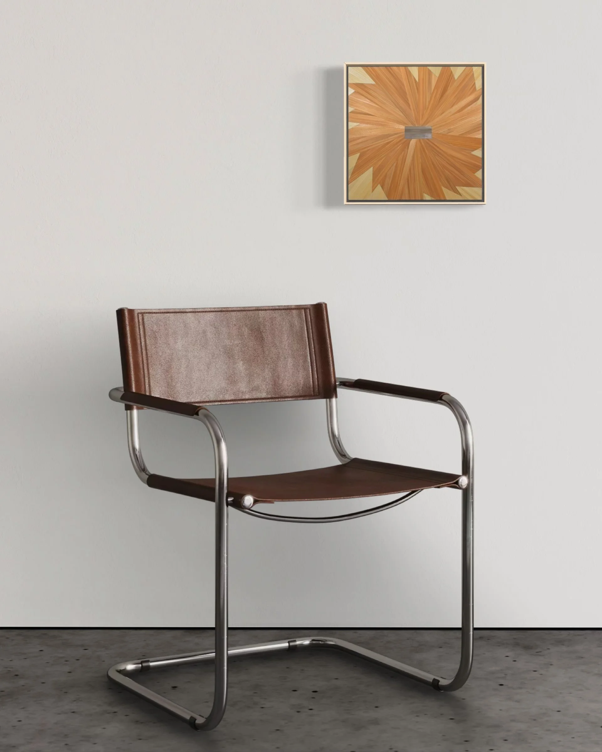 Straw marquetry panel in a pinwheel composition of amber and orange mounted on a white wall above a modern chair; small-format contemporary fiber art in an interior setting