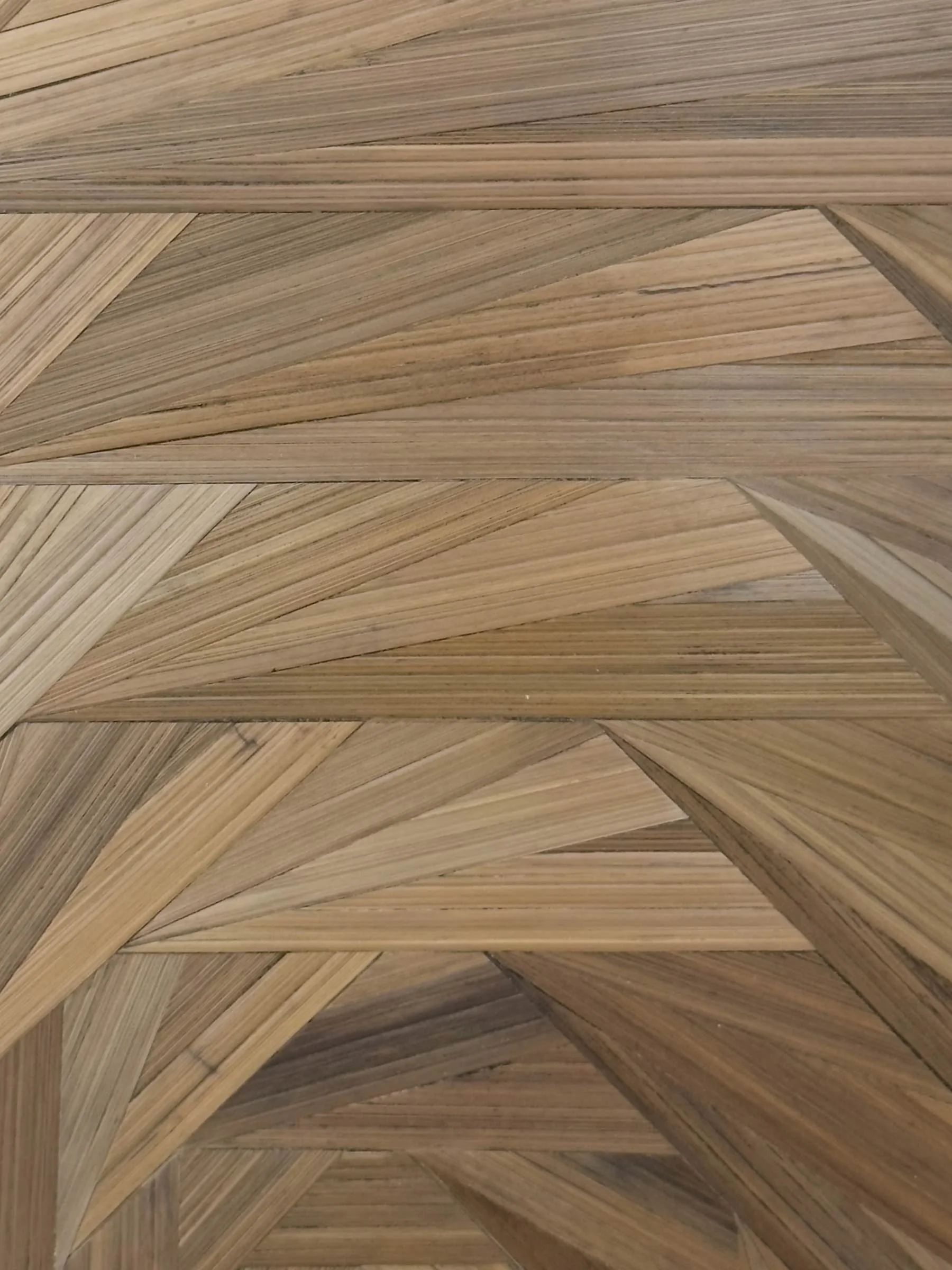 Close-up of hand-laid rye straw marquetry surface showing grain texture, warm gray-brown tonal variation, and geometric facets of the octagonal spiral pattern