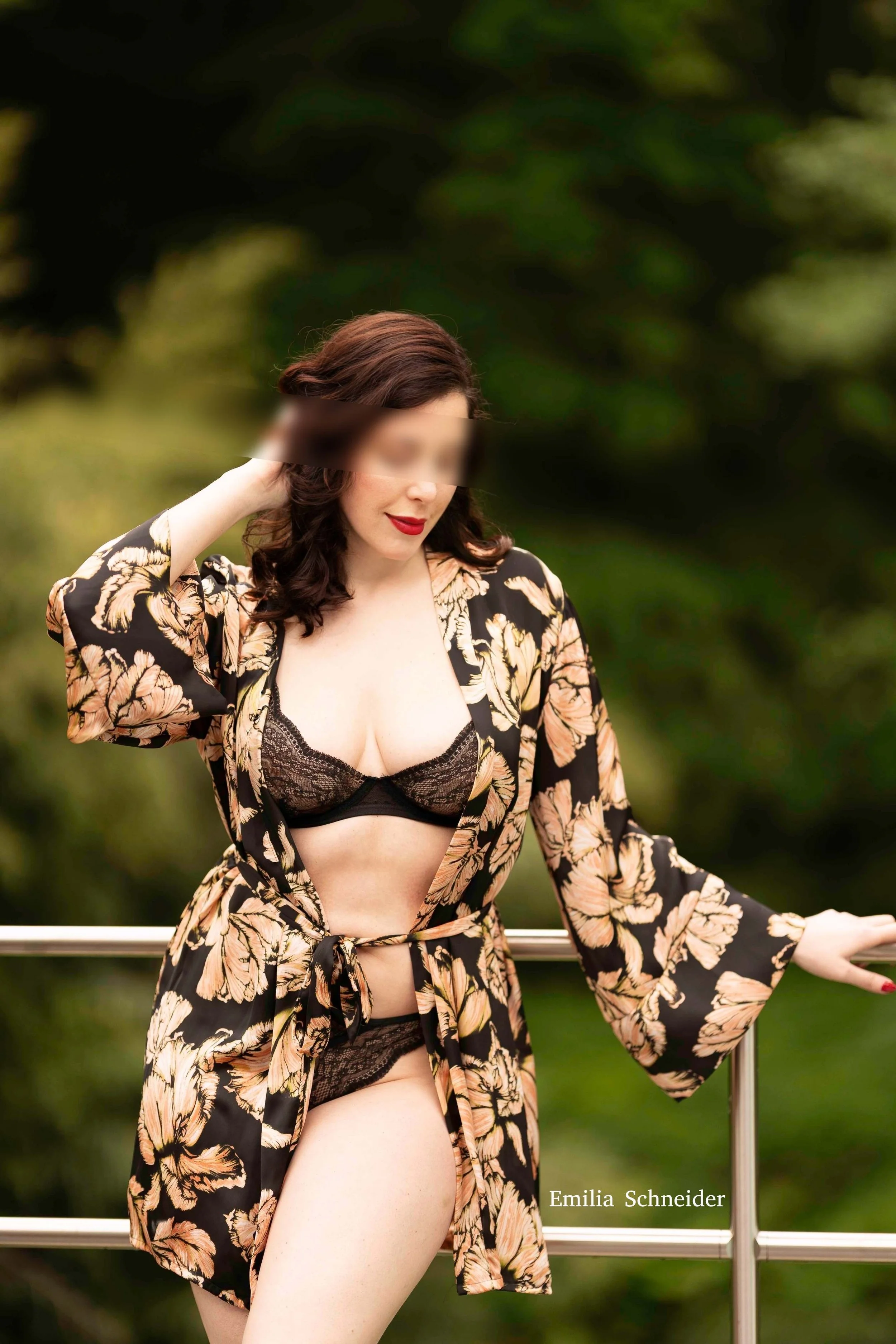 Emilia Schneider im schwarzen Spitzen-Dessous mit floralem Kimono in sommerlicher Outdoor-Kulisse mit grünem Hintergrund – sinnliche Independent Escort Fotografie.