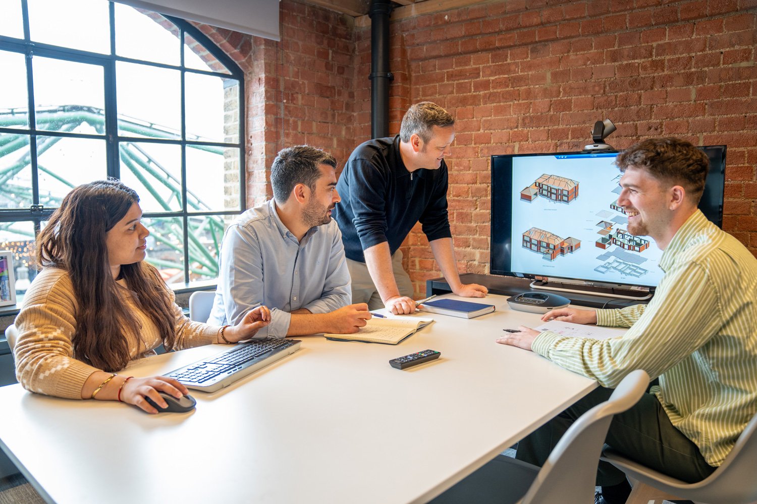 A group of Form Structural Design employees collaborating in a meeting room, reviewing a 3D structural model on a screen.