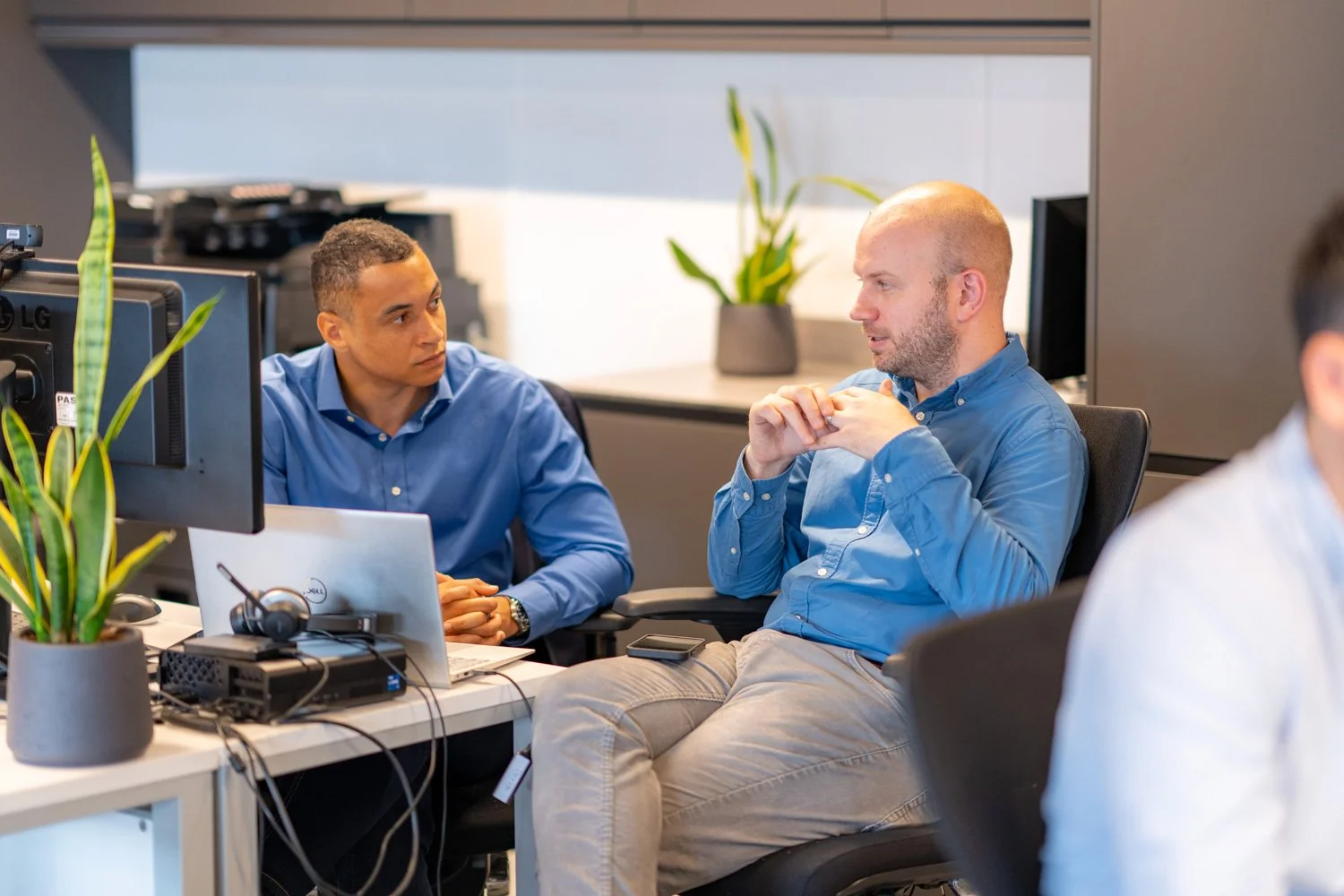 Two Form Structural Design team members have a focused conversation at their desks in an open office.