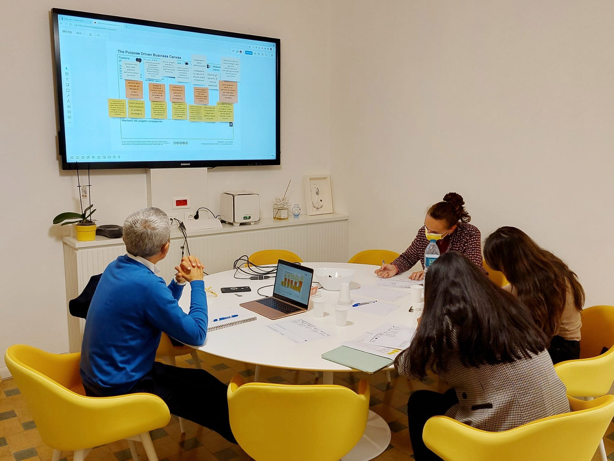 A group of people gathered around a table, focused on the content being projected onto a screen.