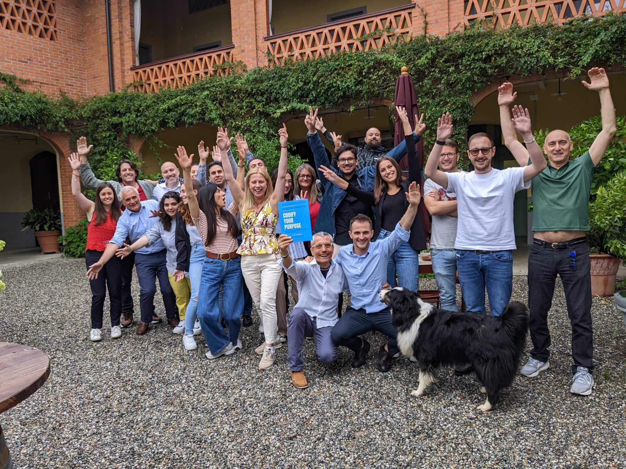  In this formal image, a group of individuals and a dog strike a pose while showcasing the book "Codify Your Purpose"