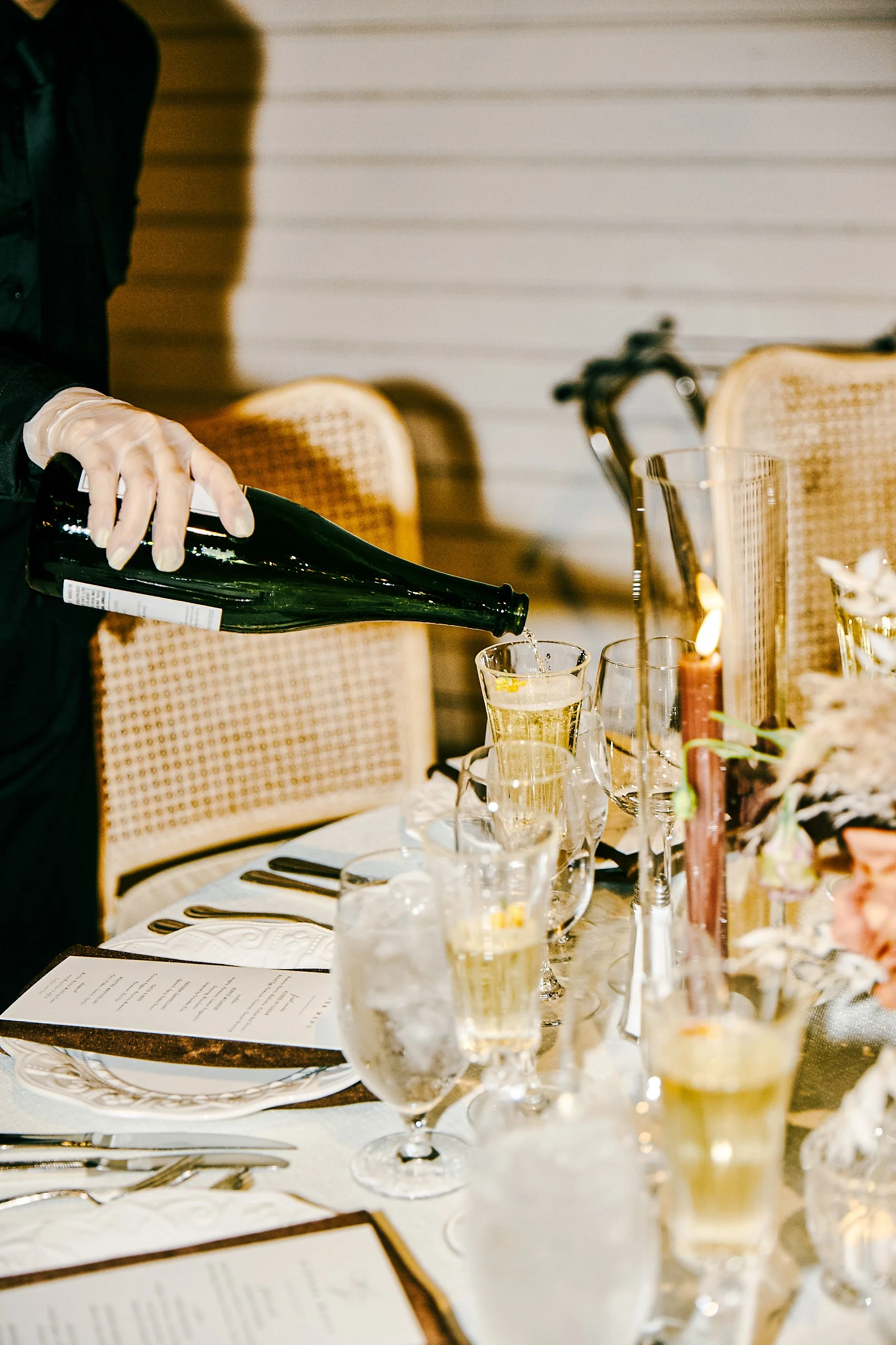 Person pouring champagne into glasses on a decorated table for a celebration or event.