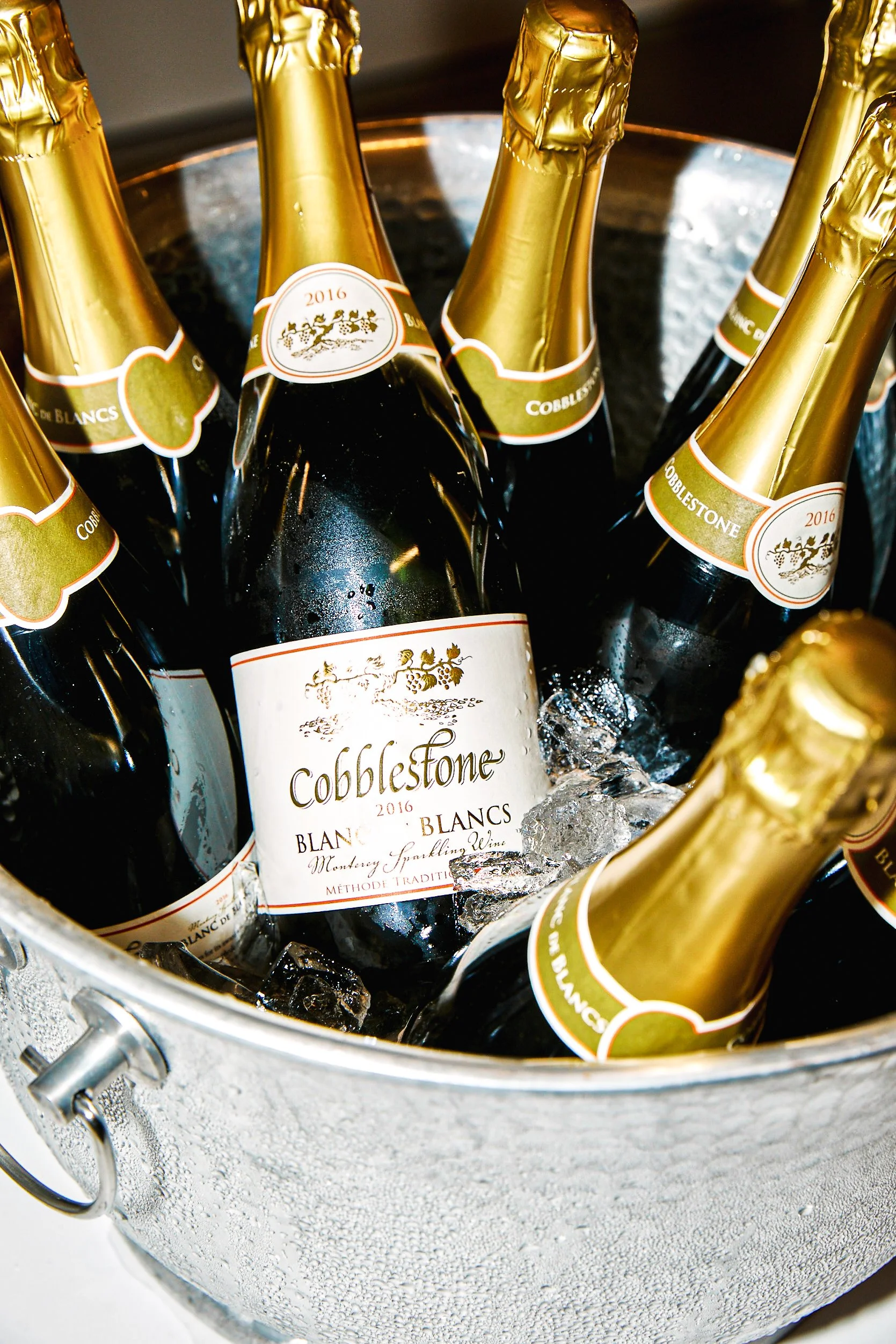 Chilled bottles of CobbleStone Blancs sparkling wine in a metal ice bucket with ice