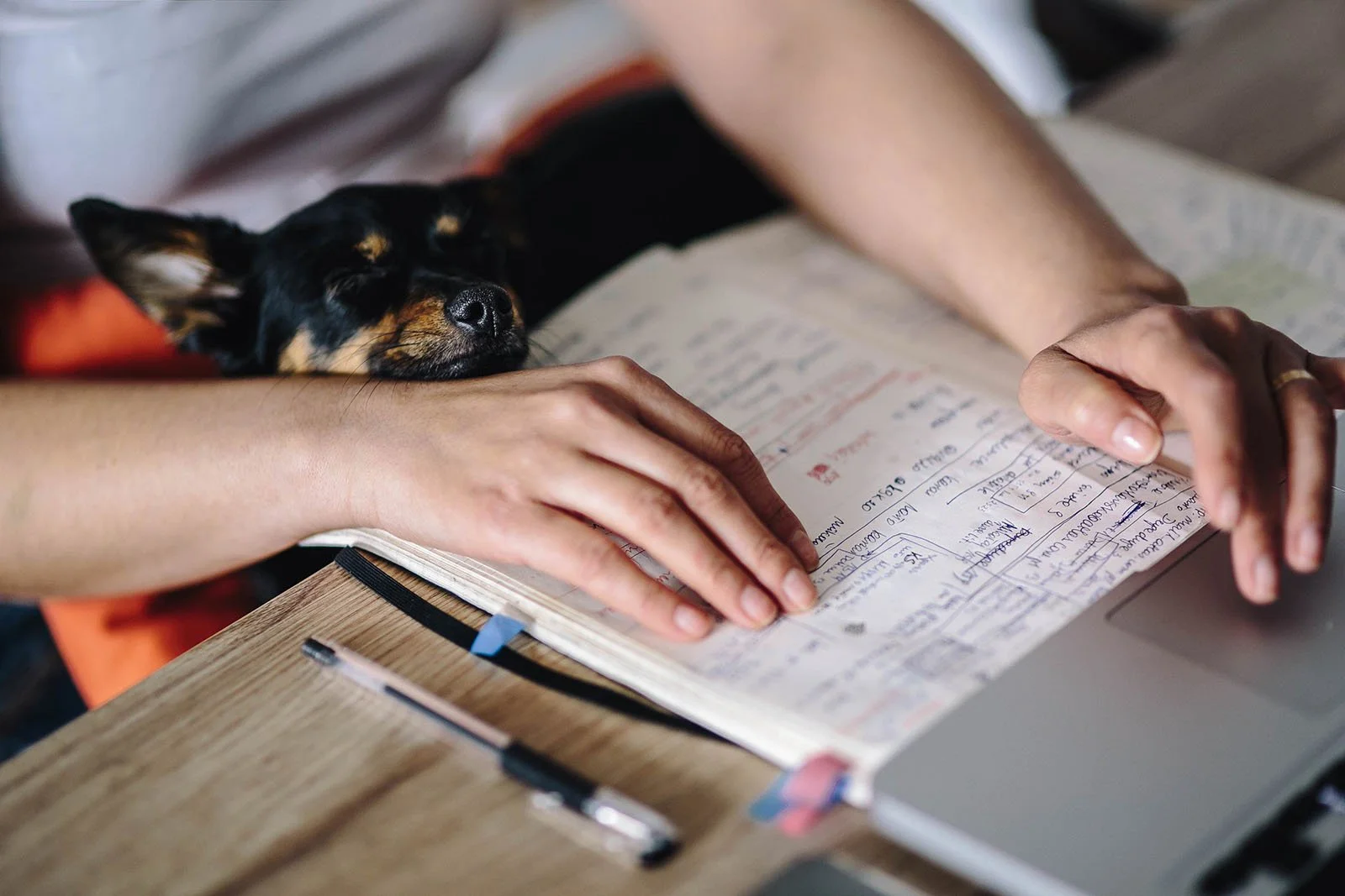 Writing a to-do list in a notebook beside a laptop, a simple ADHD planning strategy
