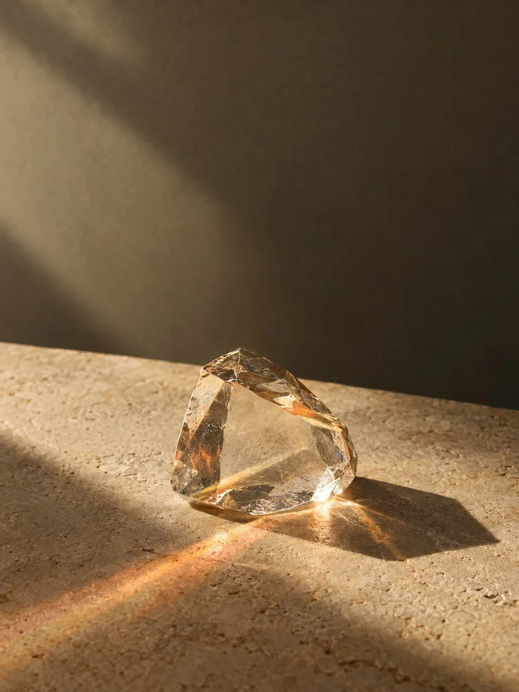 Clear glass prism casting warm light on limestone.