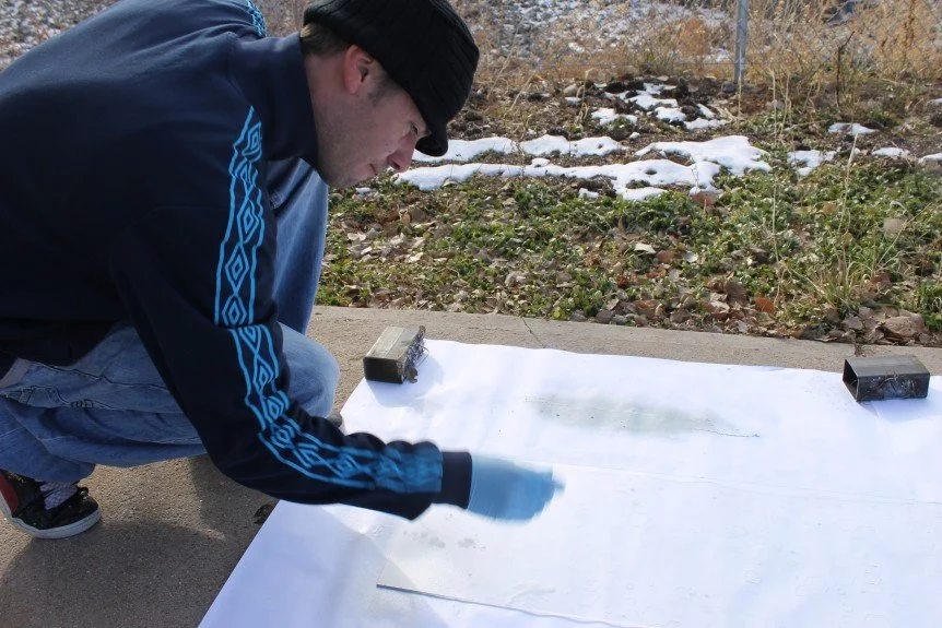 John Santos, local visual, music and graffiti artist, applying paint to bench “windows” to articulate four seasons of pollination.