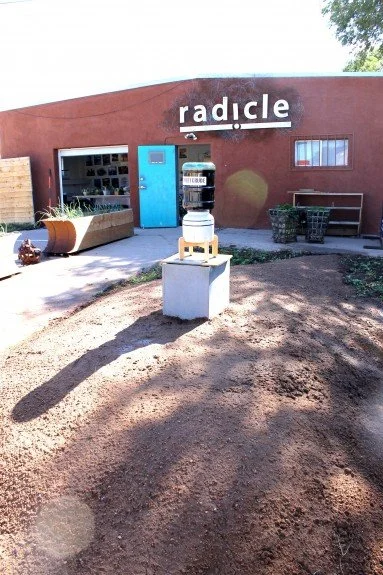 Water dispenser filled with oil sits atop pedestal in mounded grave indicating the death of water, the drying of life-giving resources and the high value of oil.