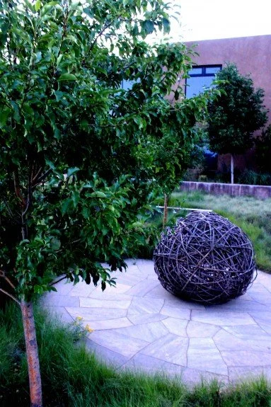 Willow sculpture by Connie Schaekel graces circular flagstone patio surrounded by Spring Snow crabapples.