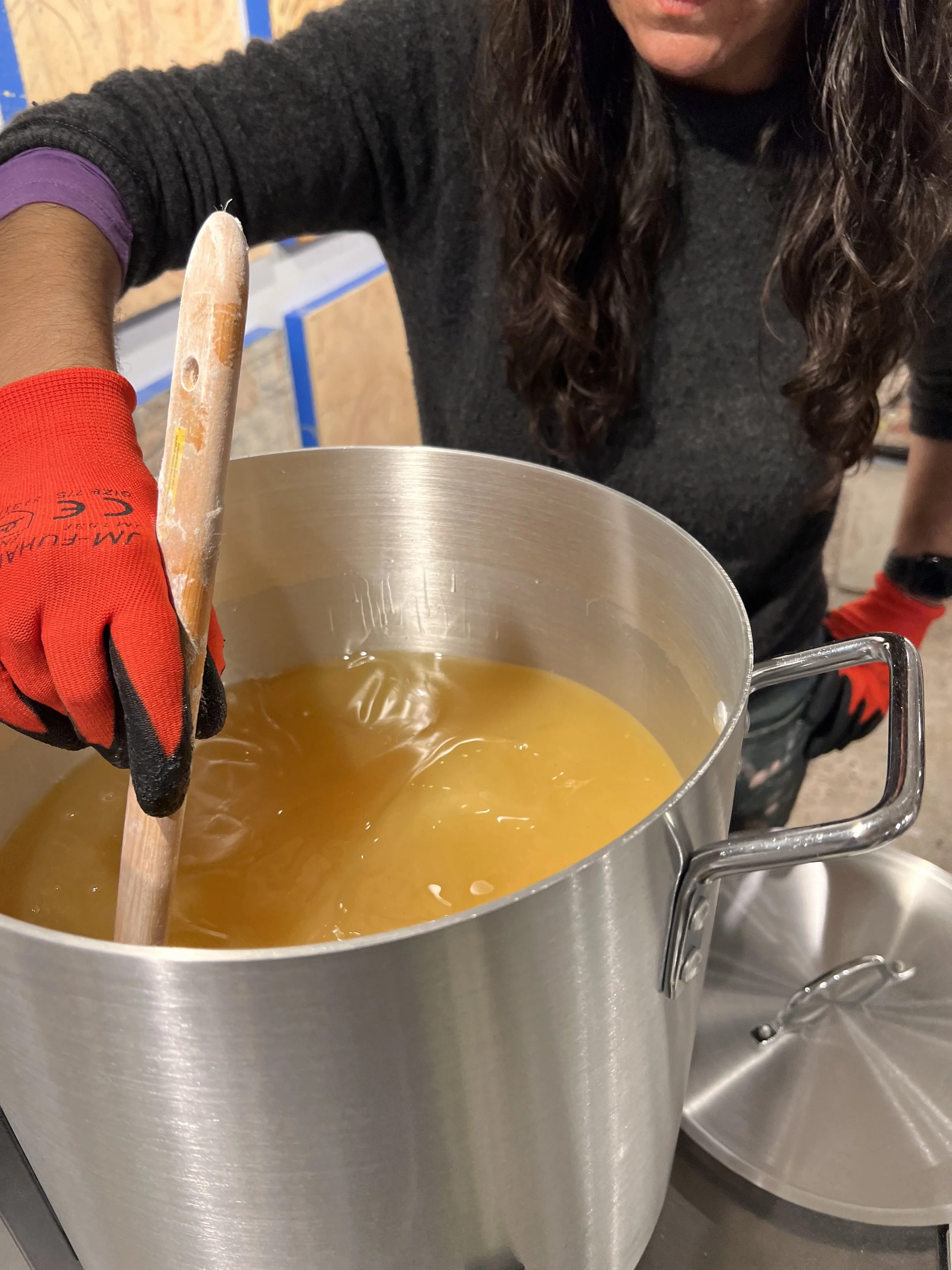 Elise stirs the melting pot of wax