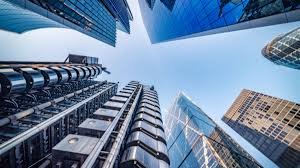 Looking up at modern skyscrapers with glass facades in an urban cityscape.