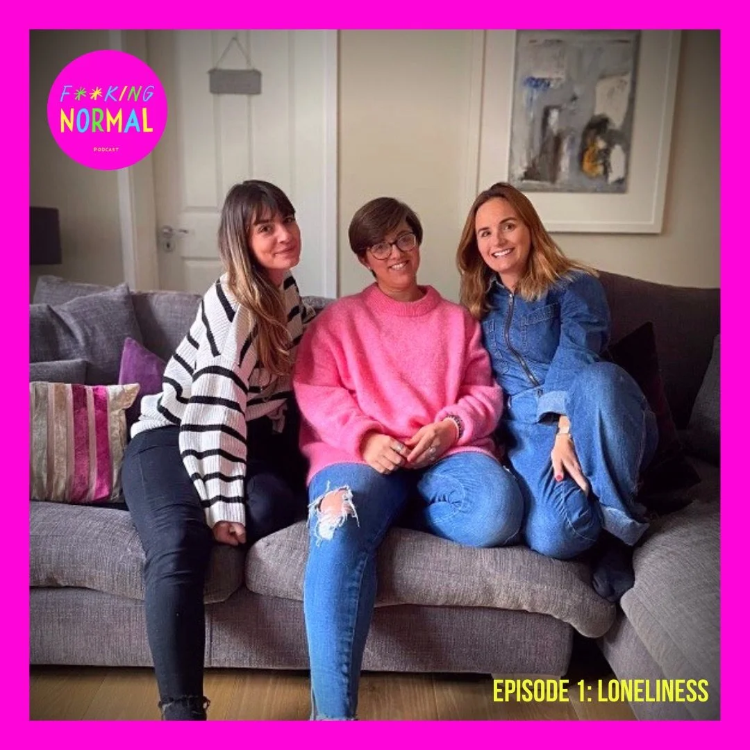 Three 30+ white women on a sofa. From left Rina is wearing a black & white striped top Gen is wearing pink jumper, Lauren wears a denim jumpsuit. The image is framed in a bright pink border with the FN logo in the top left corner Episode 1 Loneliness