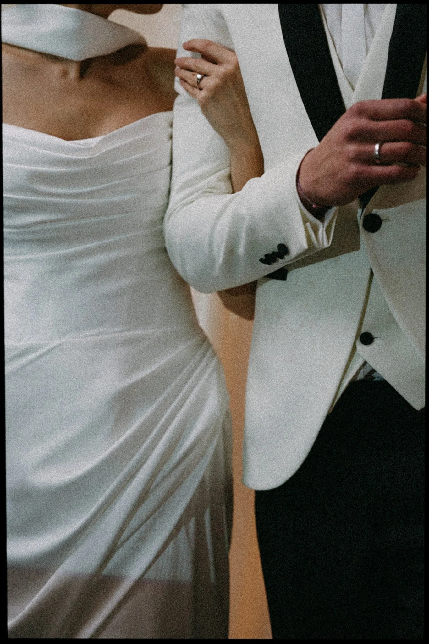 Close-up of a bride and groom taking a mirror selfie at their wedding, showing their wedding attire and rings.
