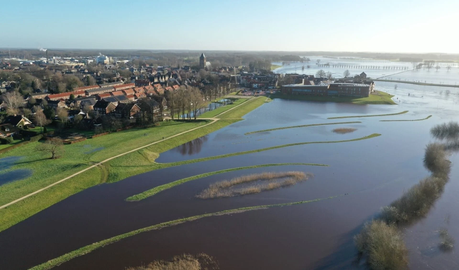 Luchtfoto van een dorp en waterlandschap met meren, grasvelden en een woongebied.