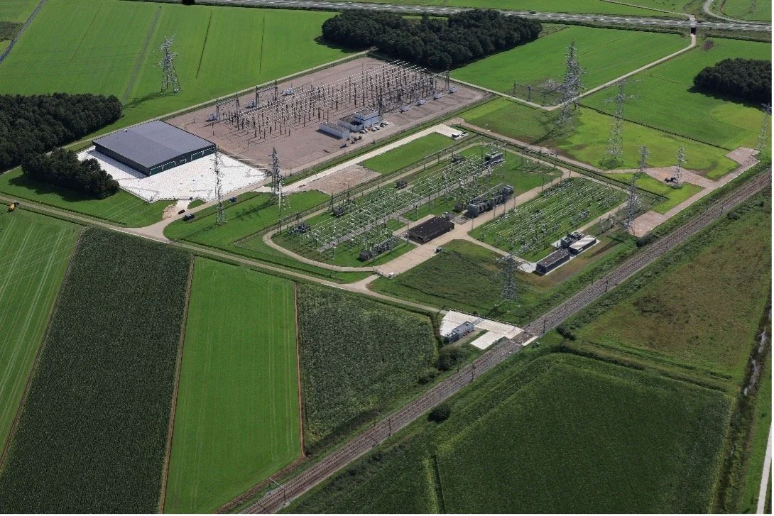 Aerial view of an electrical substation surrounded by green fields and farmland.