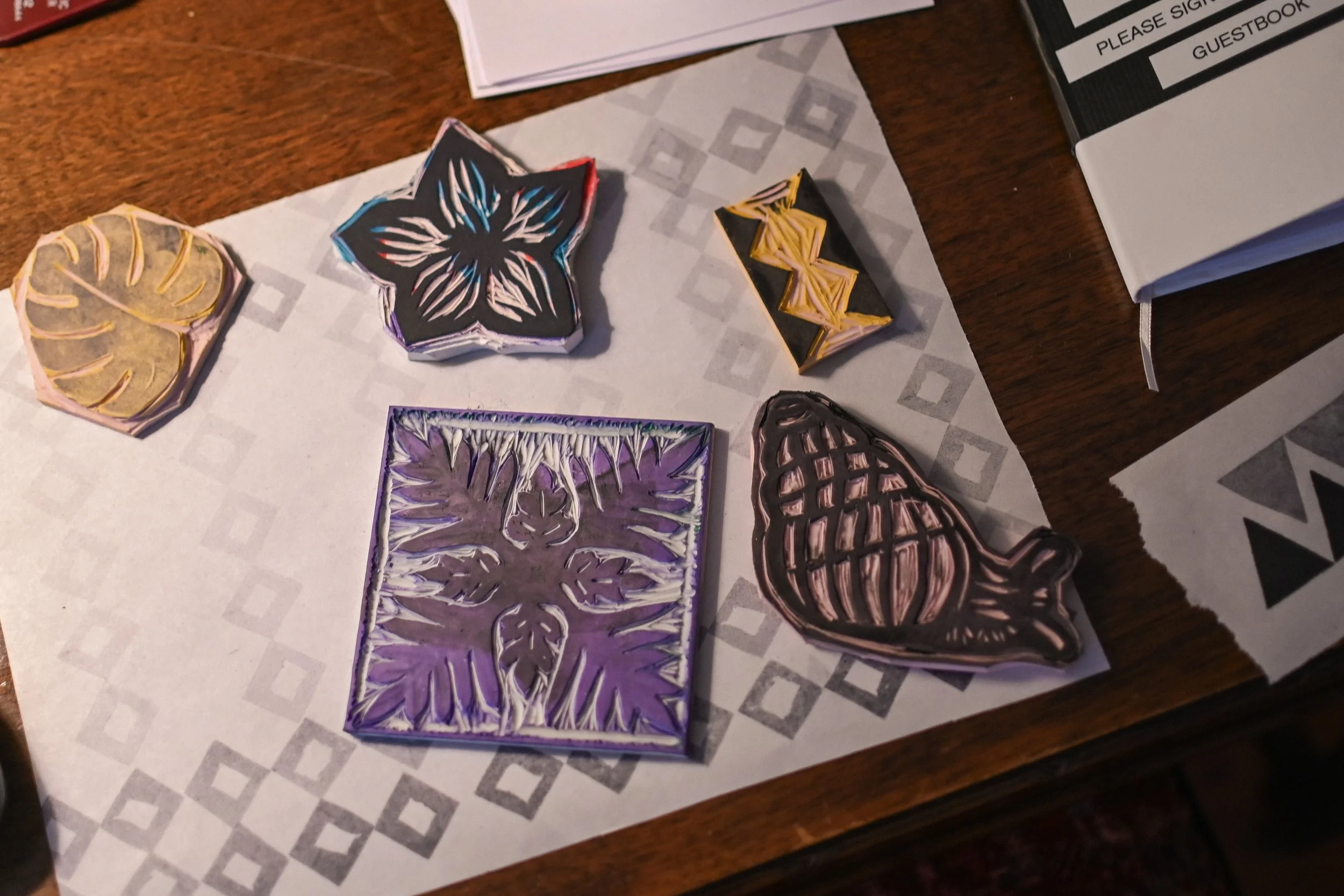 Colorful decorative stickers of a leaf, a flower, geometric shapes, a pineapple, and a bird on a paper on a wooden table.
