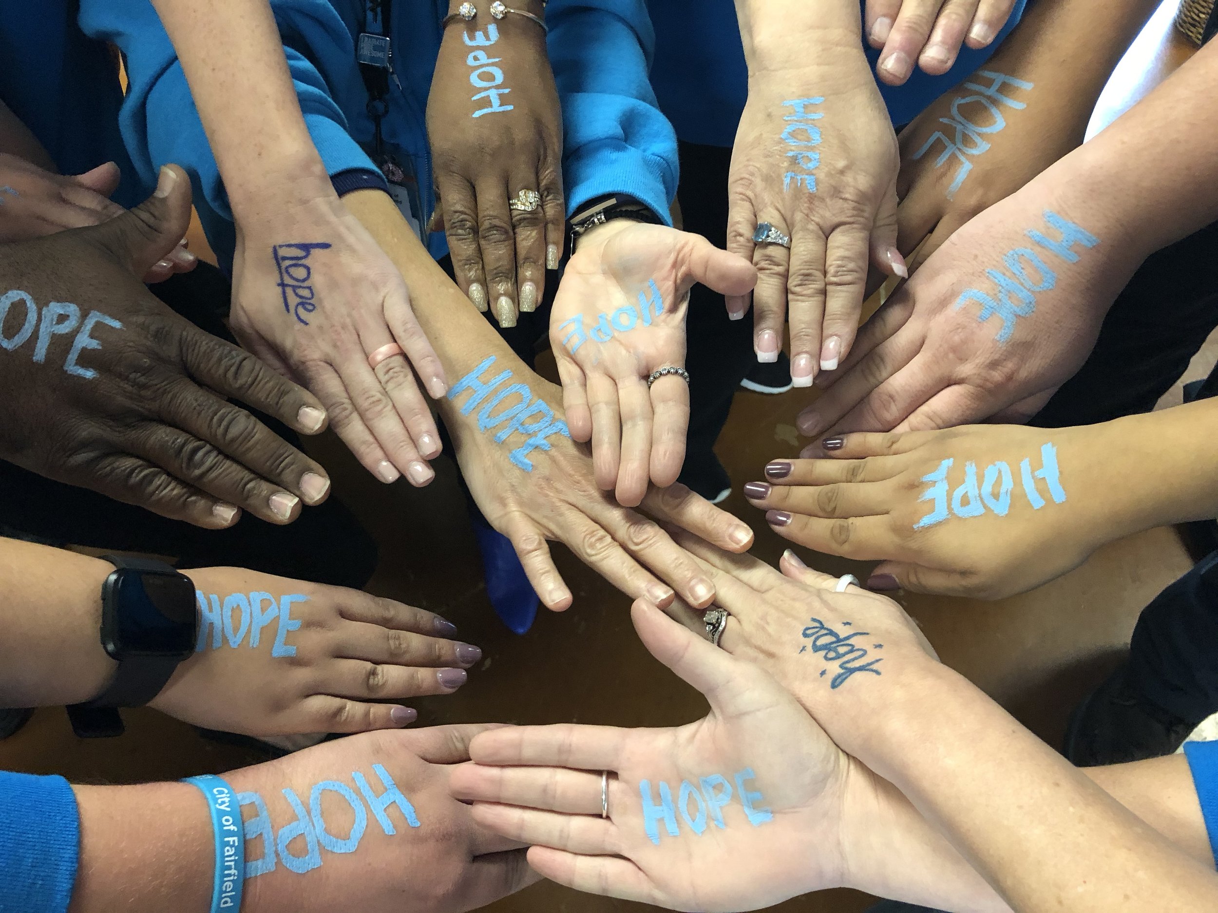 Multiple hands with 'hope' written on each hand in preparation for a cheer