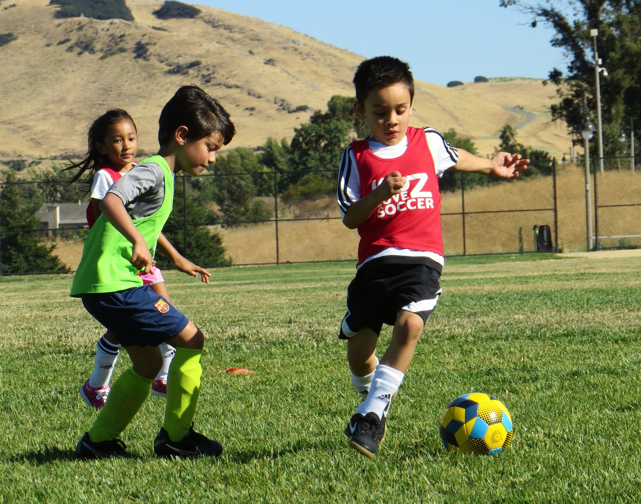Three children playing soccer on a field