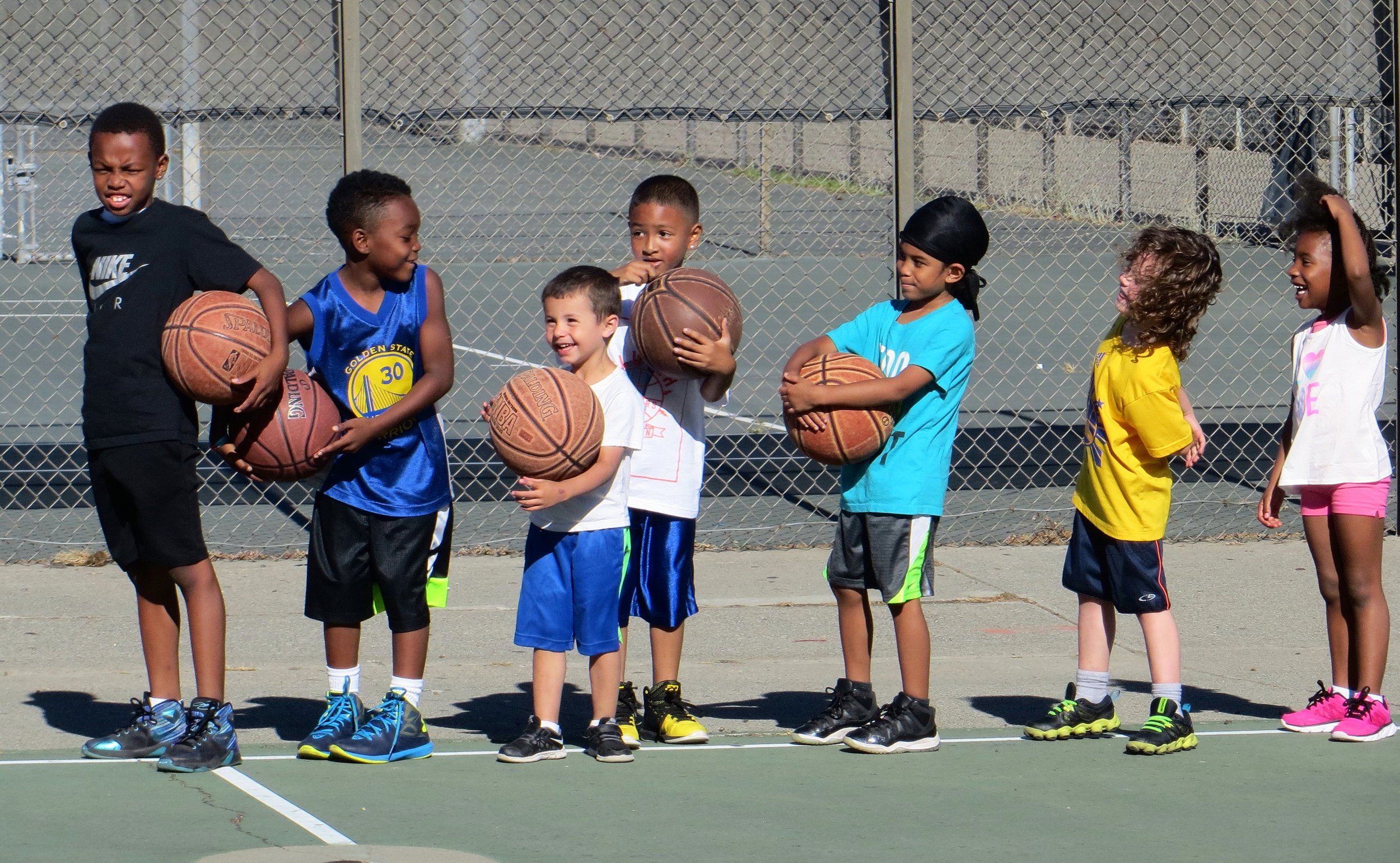 Children smiling and standing in line on a basketball court