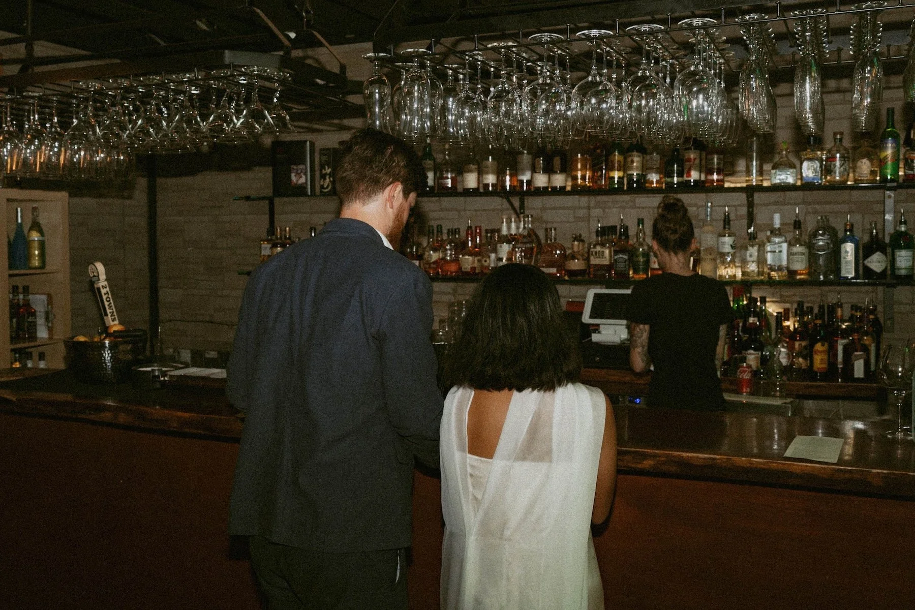 Couple ordering drinks at a moody Portland bar during their wedding welcome party