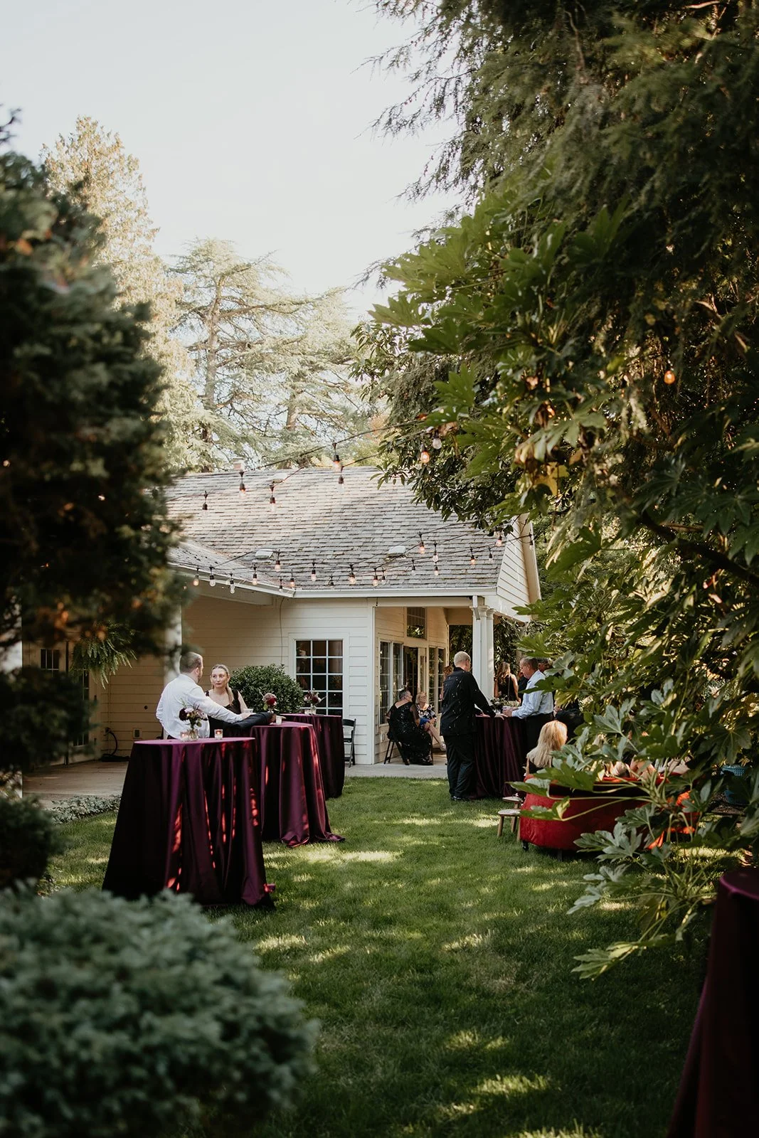 Outdoor Oregon wedding cocktail hour at Gray Gables Estate with moody burgundy linens and string lights
