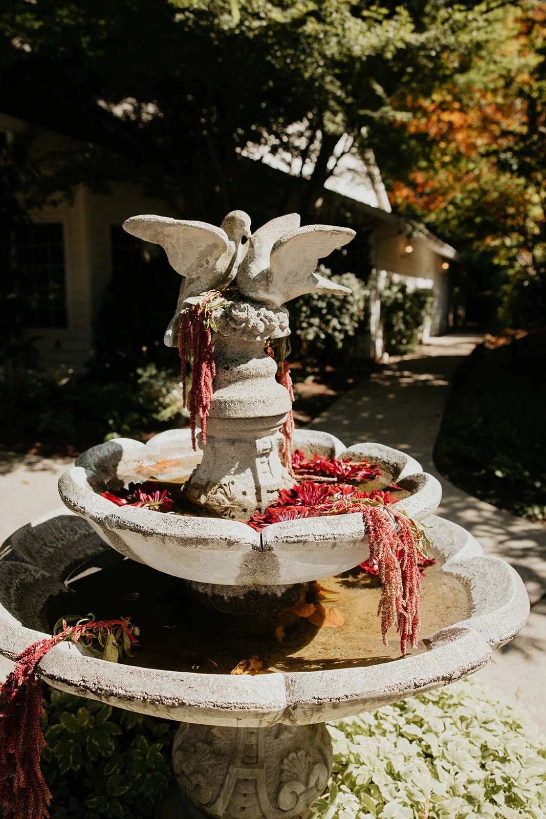 Unique outdoor Oregon wedding decor — stone fountain adorned with bold red florals at Gray Gables Estate
