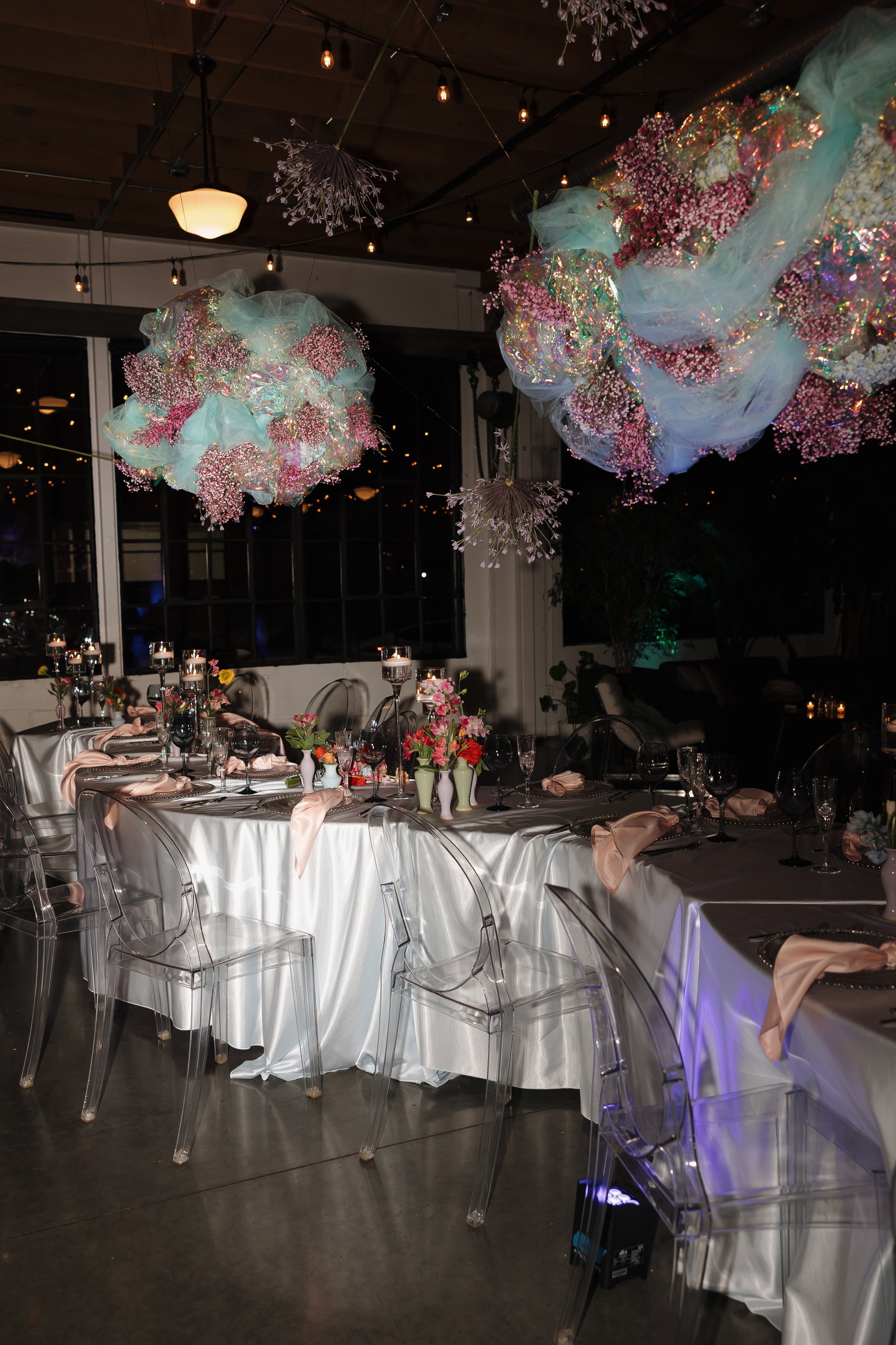 Dramatic Portland wedding reception venue with oversized hanging floral installations and ghost chairs at Castaway Portland