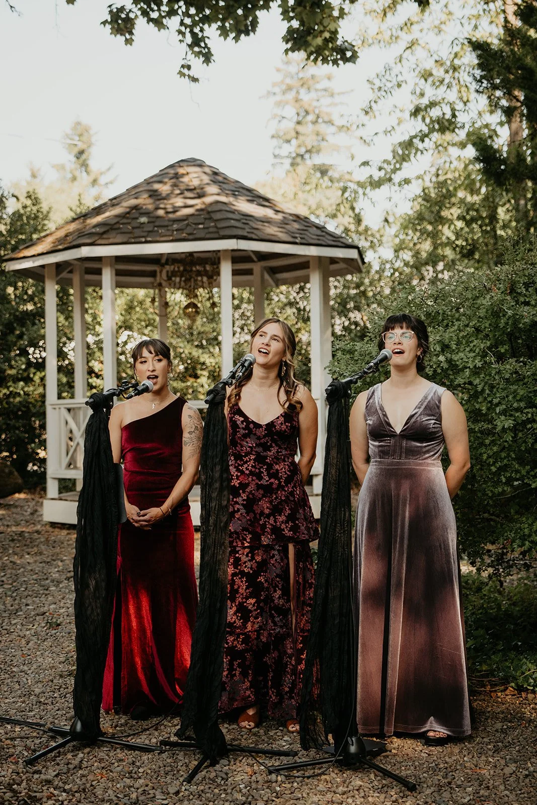 Live vocal trio performing at an outdoor Oregon wedding ceremony as a unique alternative to traditional music