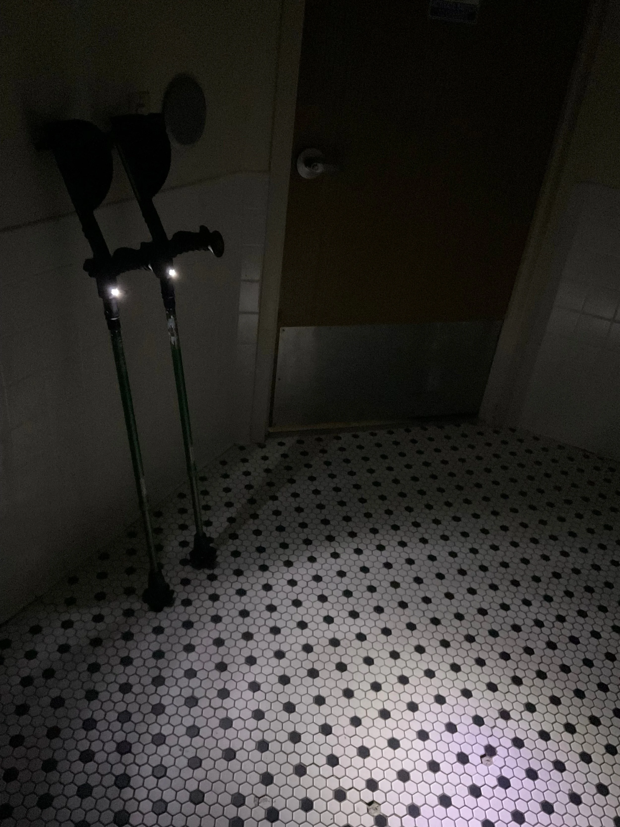 A dark bathroom illuminated only by the two LED lights in the Ergoactive crutches. The lights illuminate a circle with about a four foot diameter.