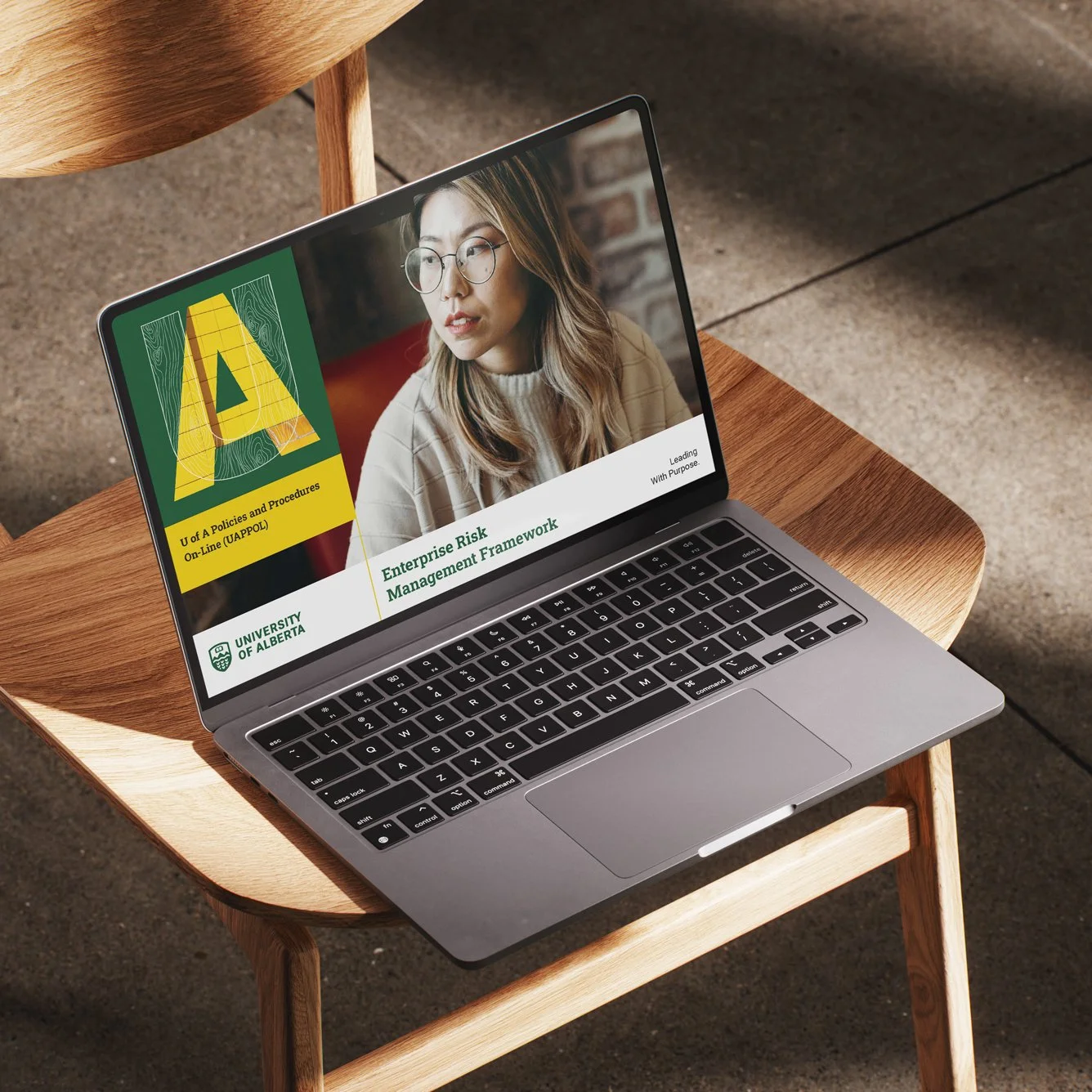 Laptop displaying University of Alberta content, Enterprise Risk Management Framework on screen, placed on a wooden chair.
