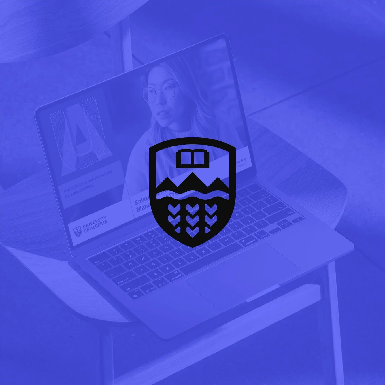 Open laptop on a wooden chair displaying University of Alberta webpage, overlaid with an academic crest design, all in a blue monochrome filter.