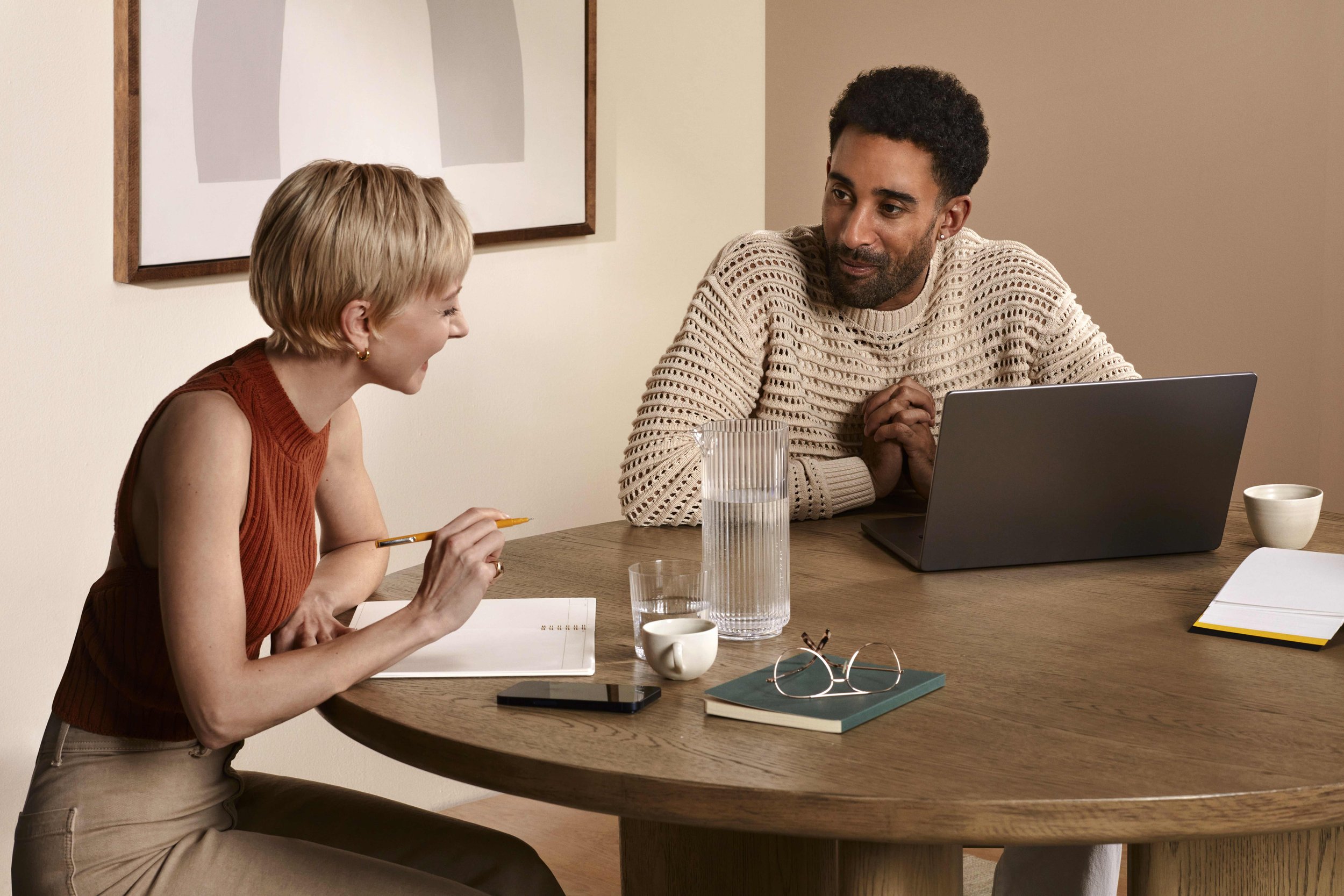 Man with laptop collaborating with woman holding notebook