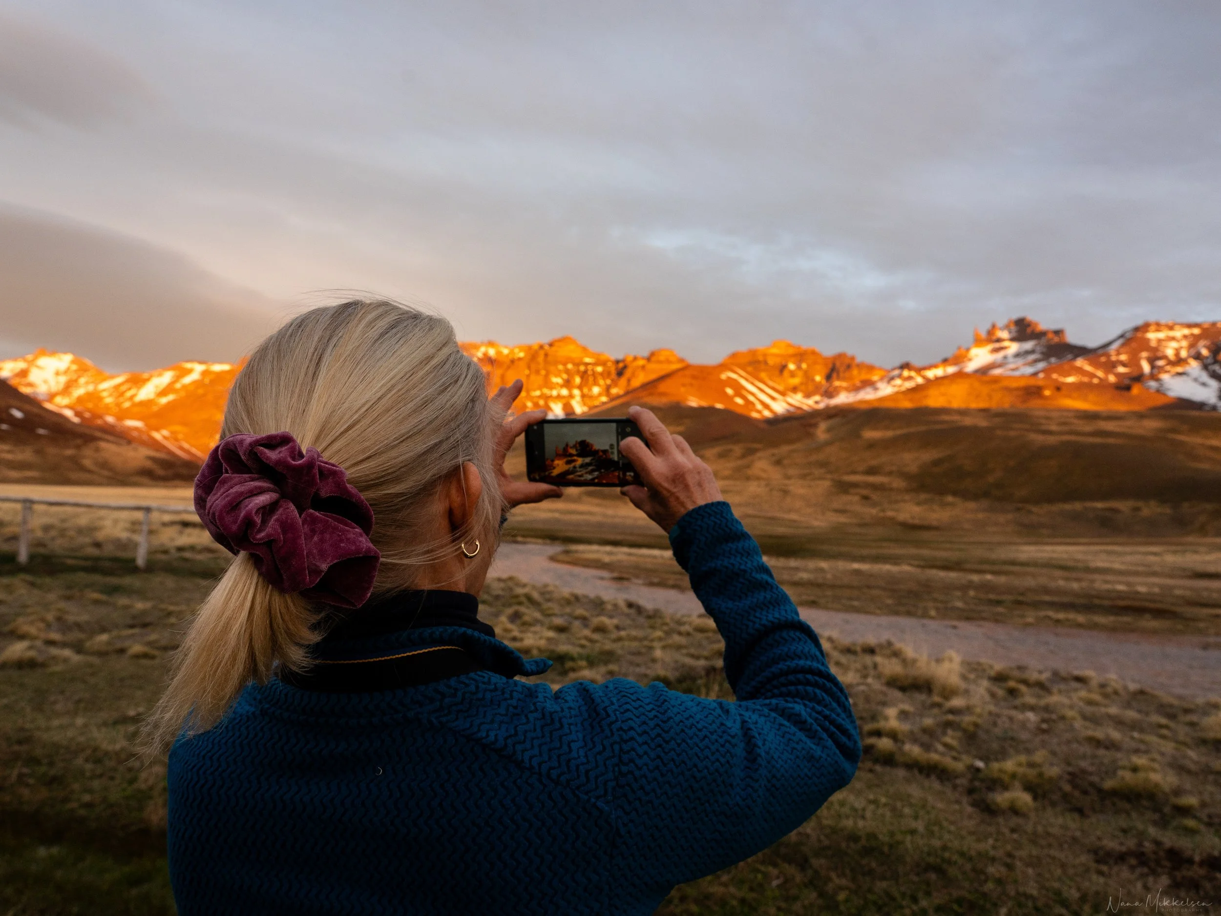 A guest photographing the sunset over Sierra Baguales, as the last light of the day illuminates the peaks of the Baguales mountain range.