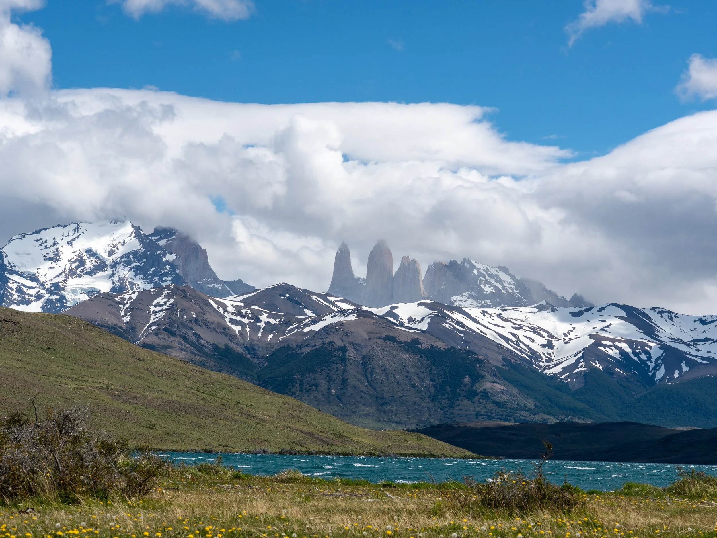 The crystal-clear waters of Laguna Azul reflecting the Paine Massif on a sunny day in Torres del Paine National Park.