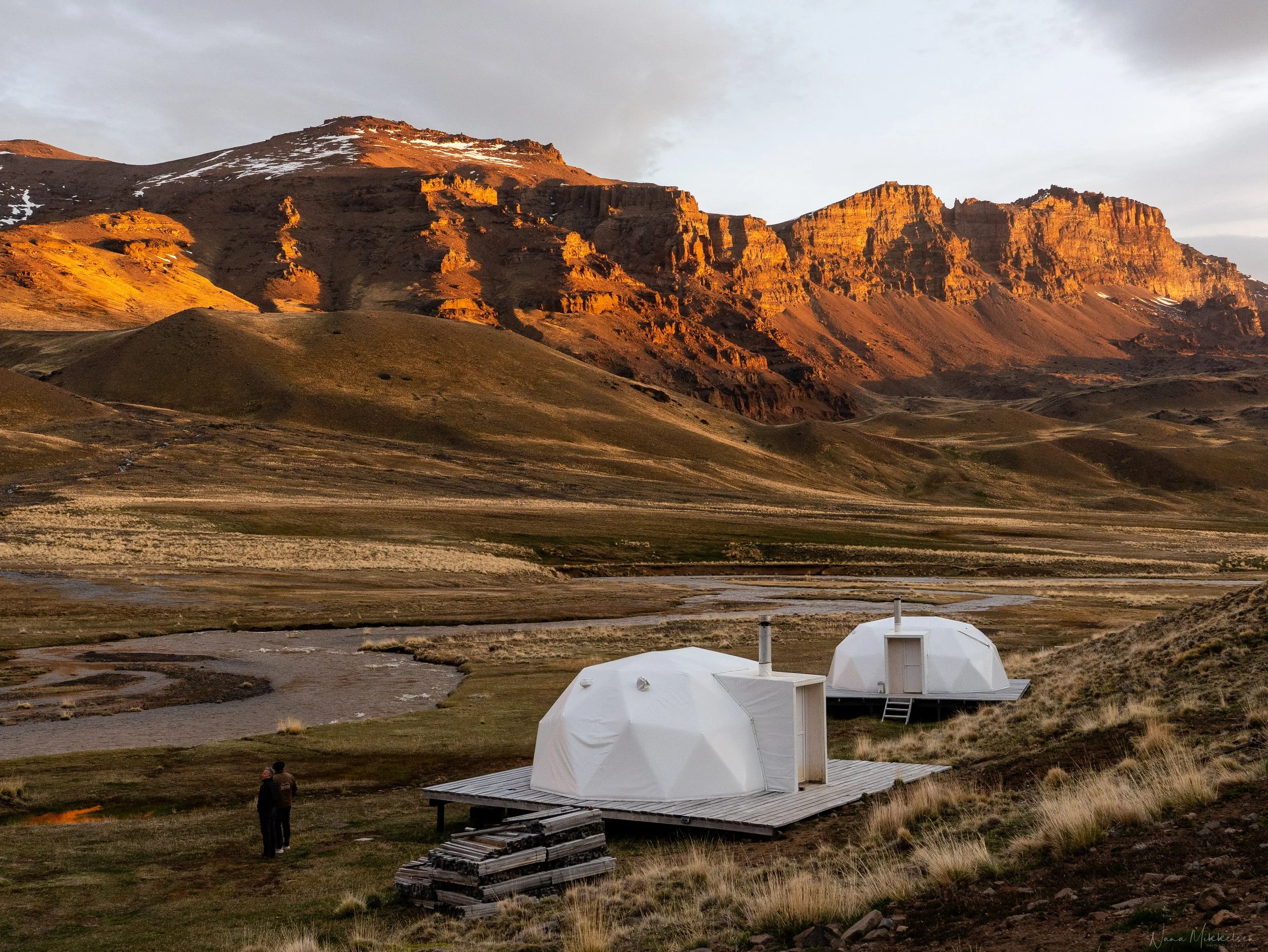 Sunset at Baguales Glamping, overlooking the Baguales River and the surrounding mountain landscape.