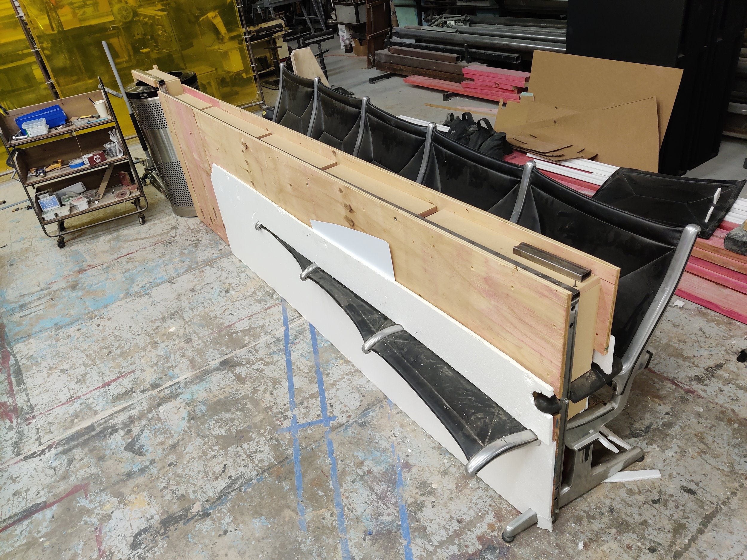 Beginning to clad custom wall frame with PVC sheet, making tight allowances for chairs to come through