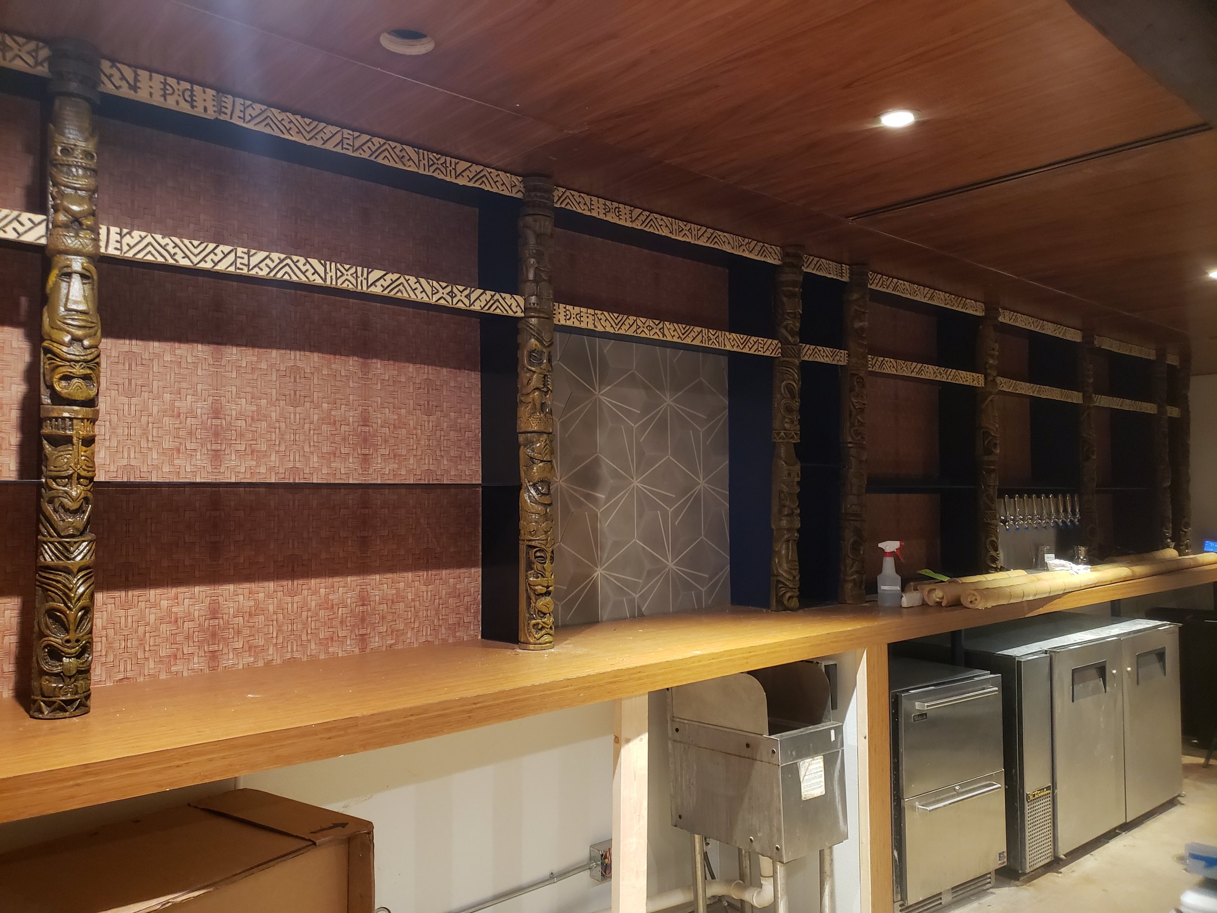 Trim and custom hand carved tiki totems behind bar cast in plastic, faux finished and painted 