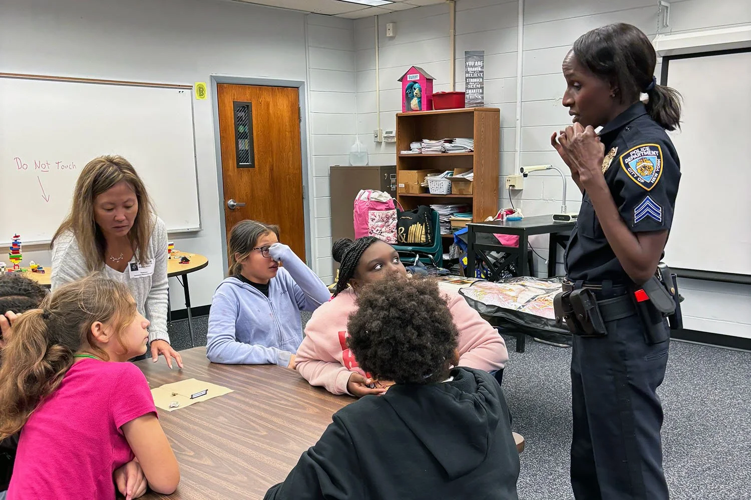 Retired NYPD officer having an intimate conversation with young girls seated at a classroom table during a mentoring visit at Lacoochee Elementary School