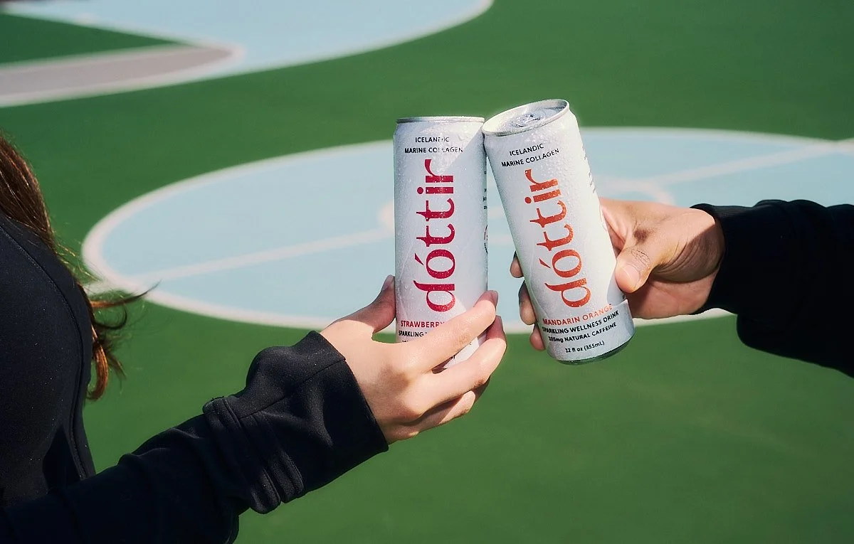 Two people toasting Dóttir collagen wellness drinks on a basketball court during the Spring into Summer lifestyle beverage campaign by NAJ Captured.