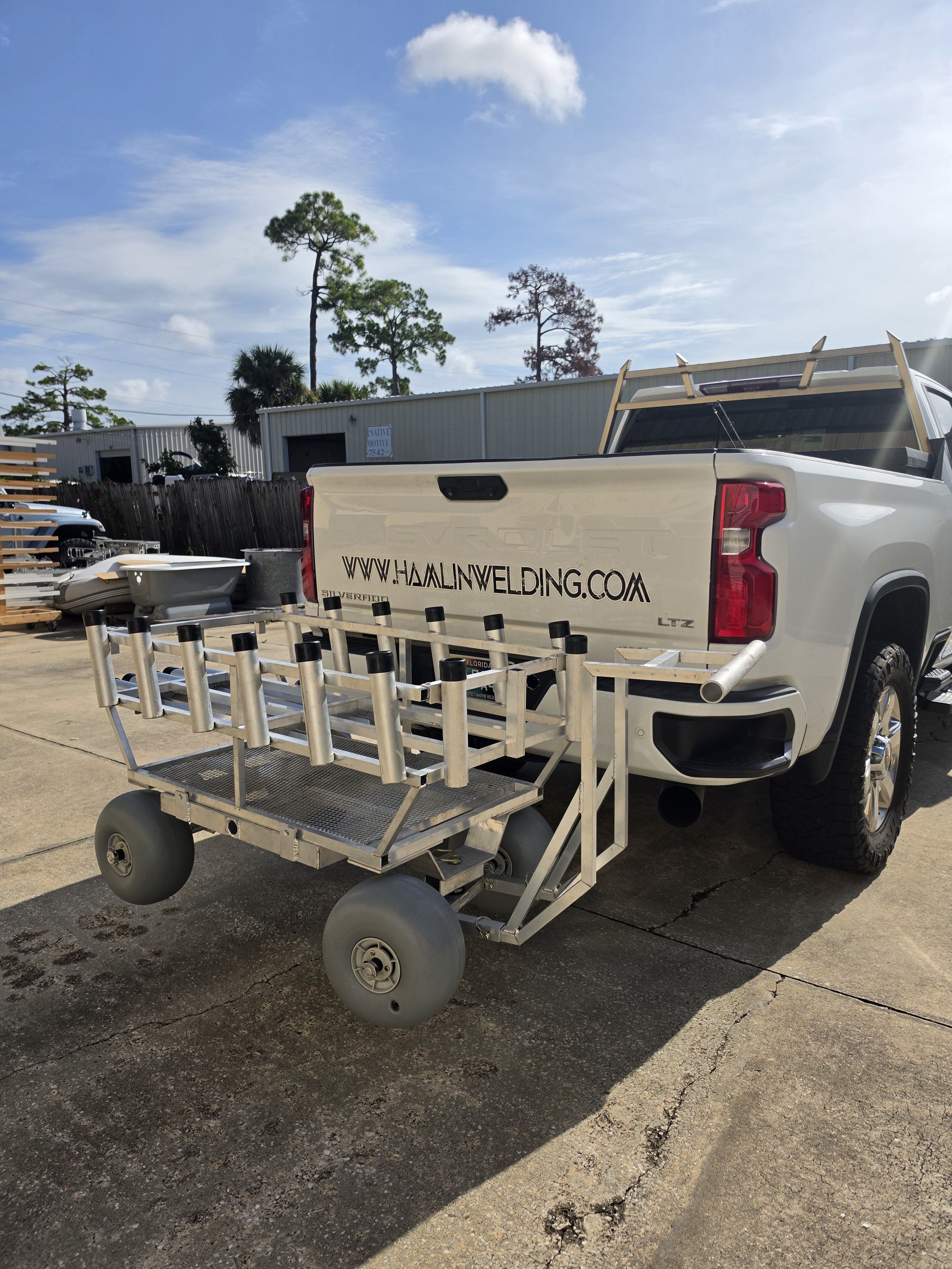 Built to carry the cart loaded — rods, cooler, and all — without flexing the frame. Hitch-mounted custom fishing cart loaded with gear on a pickup truck