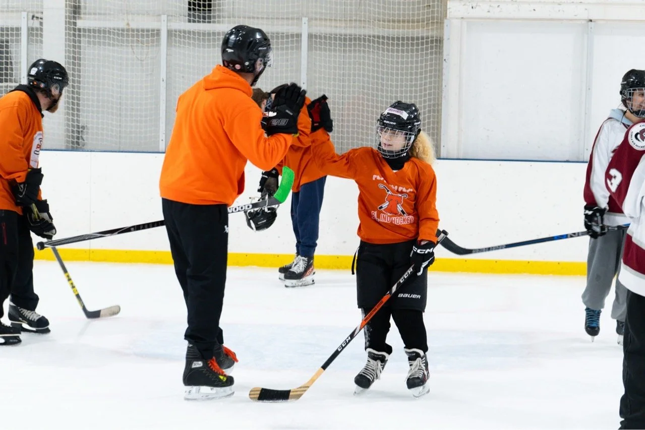 Hockey player in orange jersey high fiving a coach