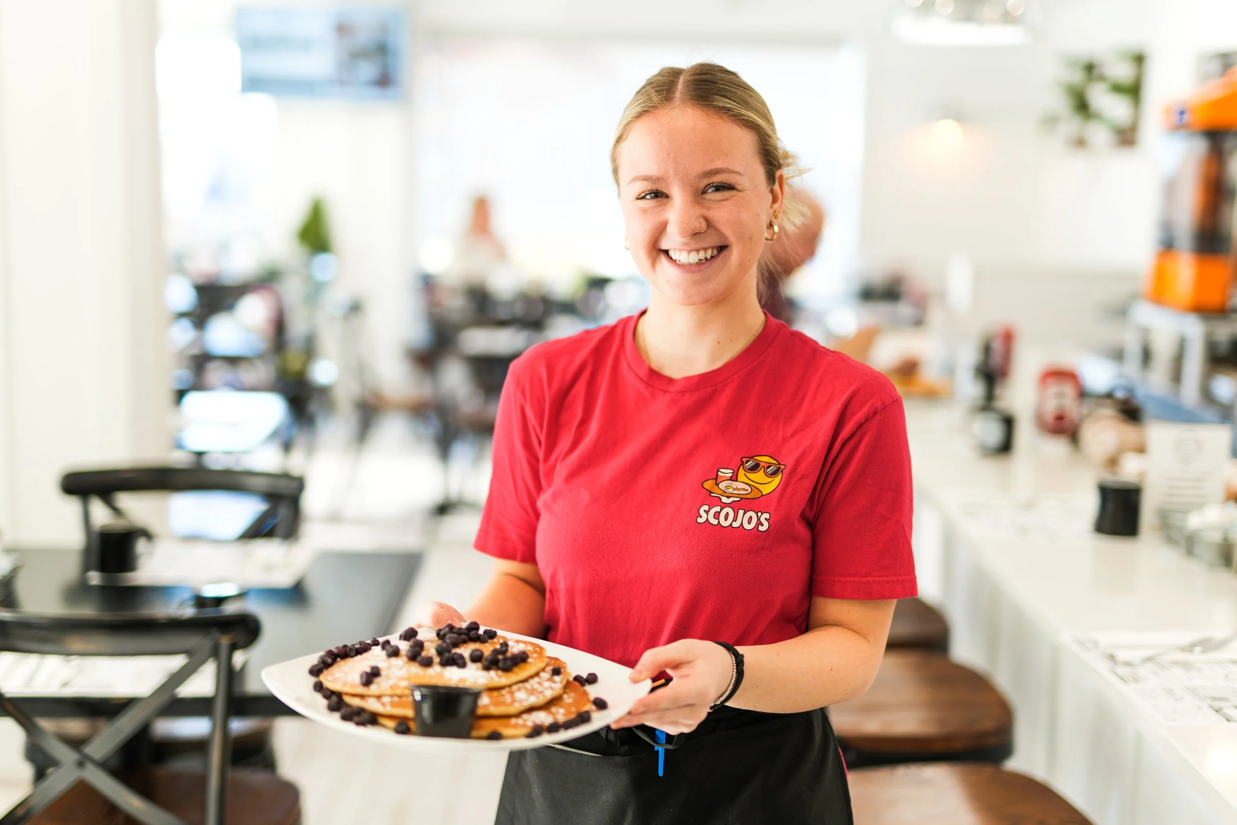 Smiling employee holding blueberry pancakes at Scojo's restaurant in Surf City New Jersey 