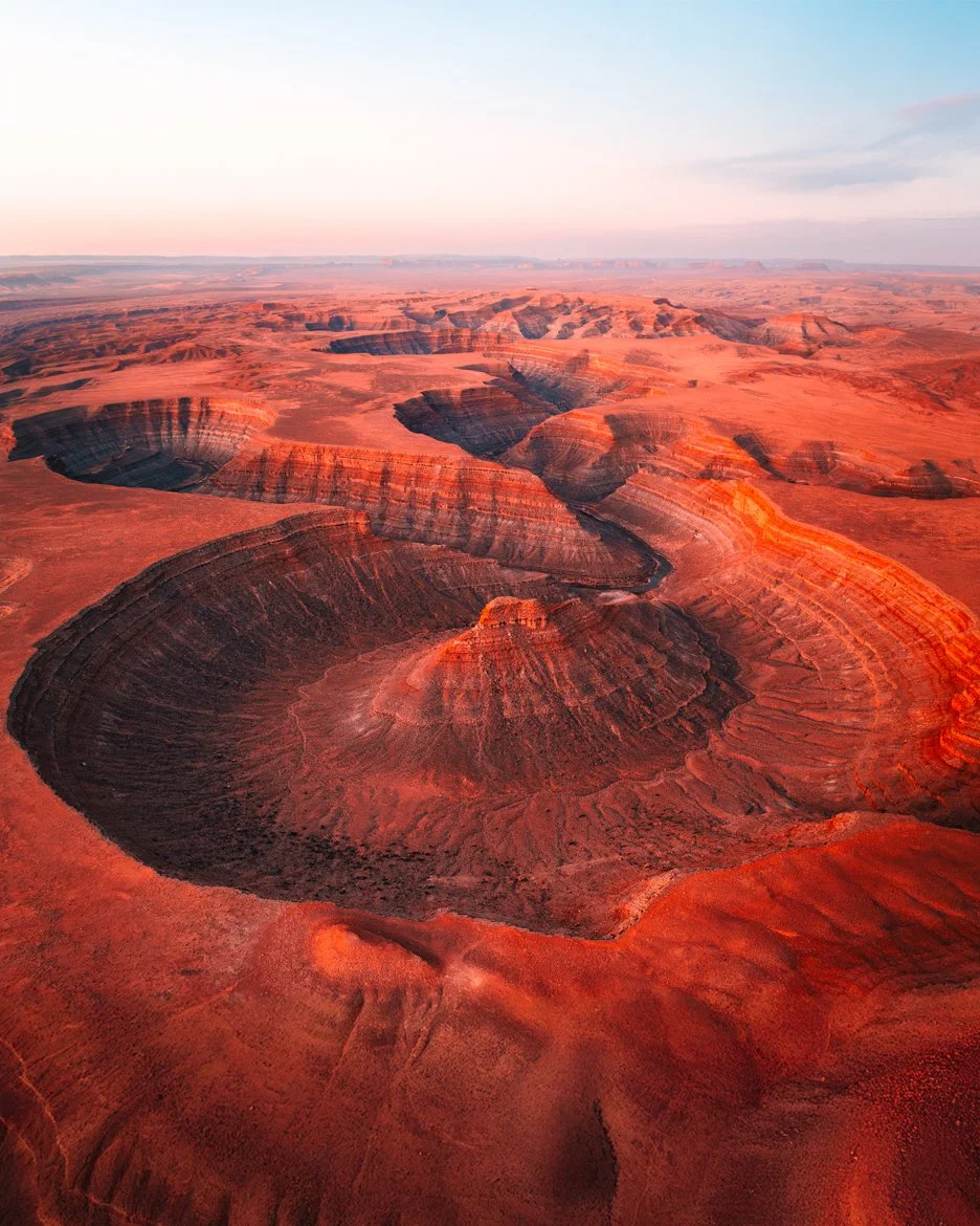 Aerial view of the Grand Canyon showcasing layered red rock formations and deep valleys at sunset.