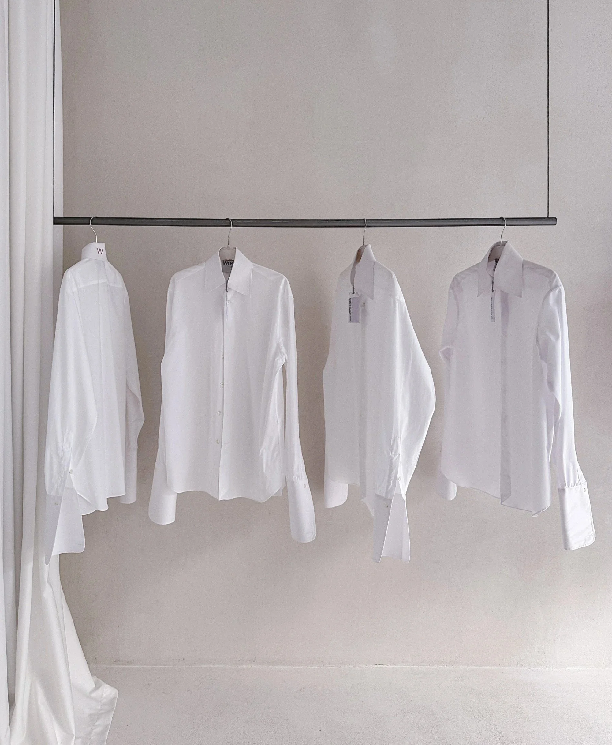 White WOERA shirts hanging on a rail in the Athens showroom